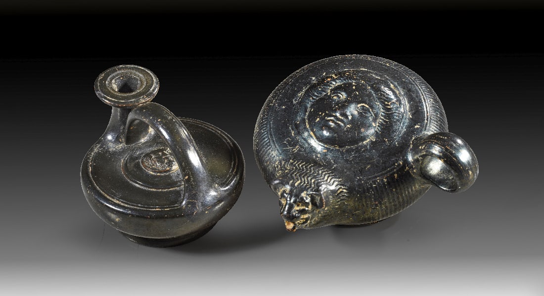 Zwei kleine apulische Ausgussgefaesse der Glanztonware.: Zwei kleine apulische Ausgussgefaesse der Glanztonware. 1. Haelfte 4. Jh. v. Chr. a) Wunderschoener Guttus mit Ringhenkel und geripptem Koerper. Plastisch ausgeformt sind oben ein Gorgoneion im