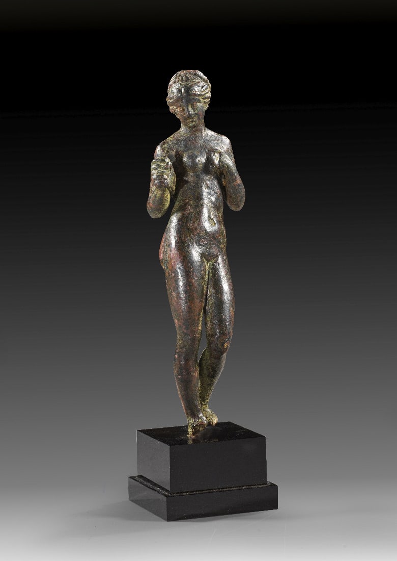 Brustbandloesende Venus.: Brustbandloesende Venus. Roemische Kaiserzeit, 2. Jh. n. Chr. H 12cm. Bronzevollguss. Kontrapostisch stehende Venus oeffnet das Strophion. Schoene rotgruene Patina, Fussspitzen gebrochen, sonst intakt