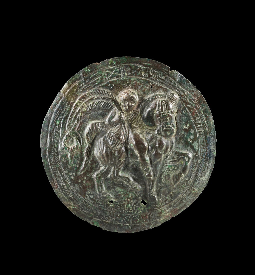 Zierscheibe mit Reiter.: Zierscheibe mit Reiter. Roemisch, 4. Jh. n. Chr. ? 10,5cm. Getriebenes Bronzeblech. Scheibe mit nach rechts trabendem Pferd, auf dessen Ruecken ein jugendlicher Reiter sitzt, der einen langen