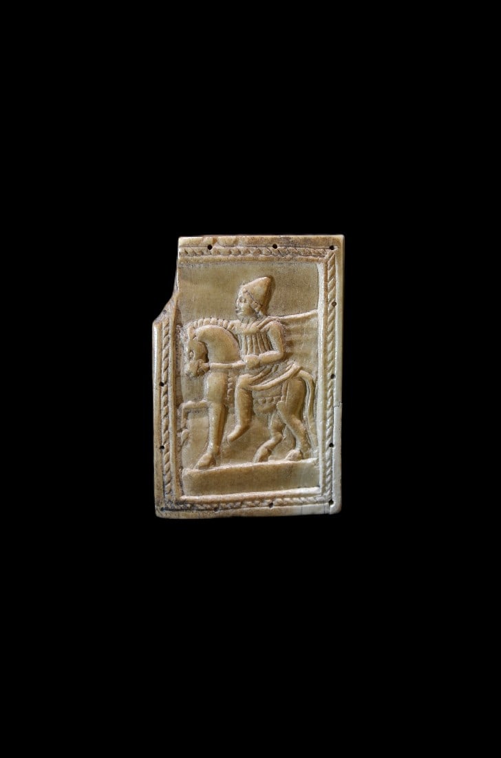 Plakette mit Dioskur.: Plakette mit Dioskur. Roemisch, 1. - 2. Jh. n. Chr. 5,8cm x 8cm. Rechteckige Plakette aus Bein mit einem abgesetzten Rand mit einer Kordelleiste. Im Bildfeld ein Dioskur mit Pilos und Lanze zu Pferd.
