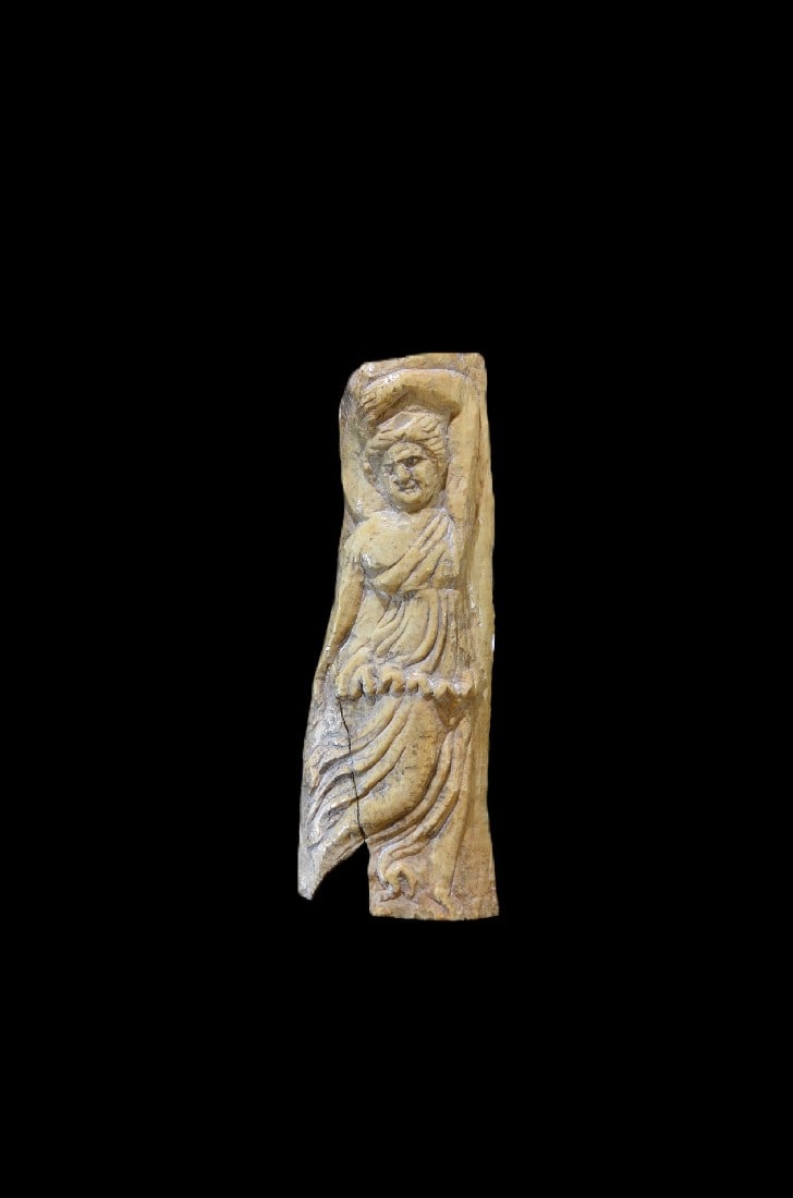 Relief mit tanzender Maenade.: Relief mit tanzender Maenade. Romano-aegyptisch, 3. - 4. Jh. n. Chr. H 15cm, B 5,5cm. Bein. Dargestellt ist eine Frau in der Bewegung mit ueber den Kopf erhobenem, linken Arm, die Rechte ist gesenkt