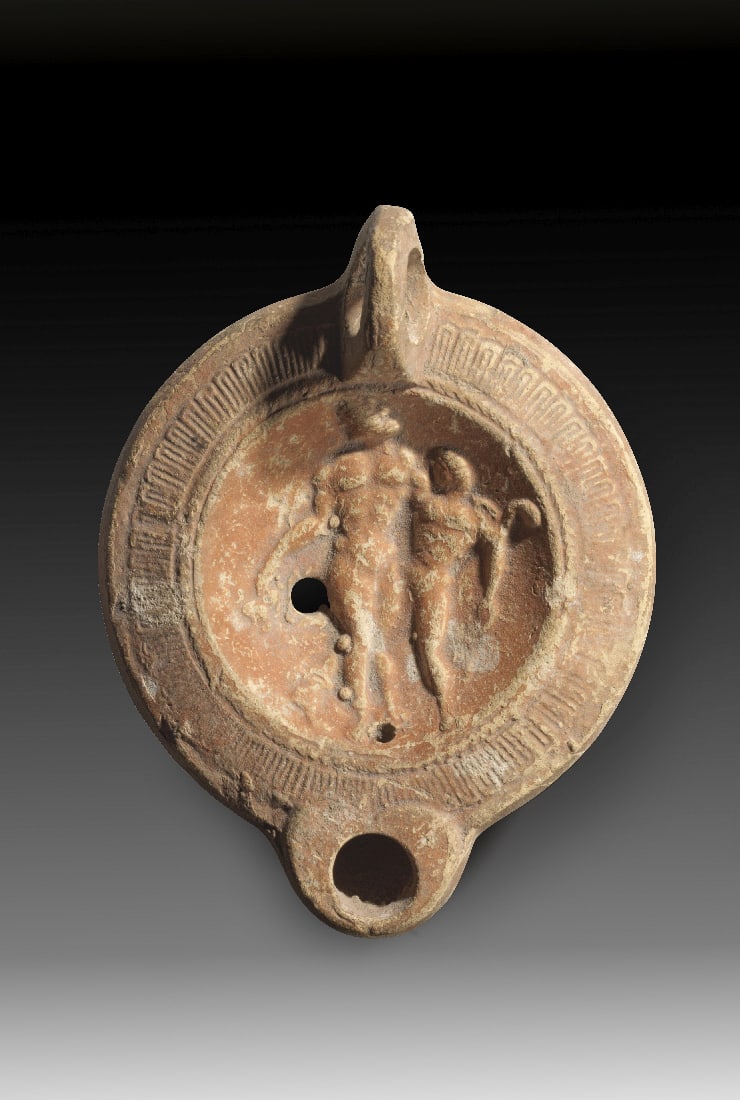 Roemische Tonlampe mit Bacchus und Satyr.: Roemische Tonlampe mit Bacchus und Satyr. Kaiserzeitlich, 1. - 2. Jh. n. Chr. L 11,3cm. Typus Loeschcke VIII mit Griff. Hellbrauner Ton mit braunem ueberzug. Im Spiegel der jugendliche und