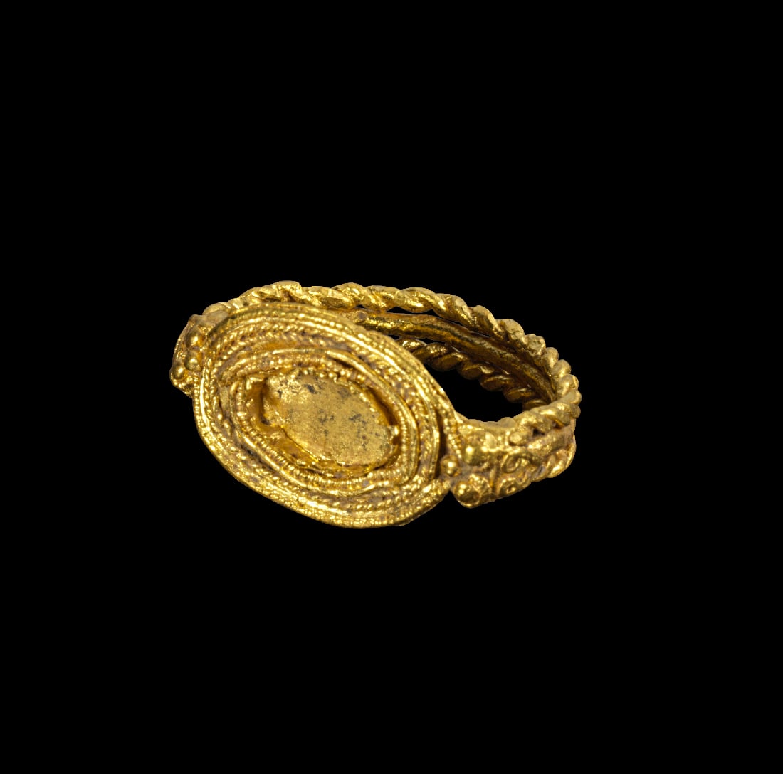 Goldring.: Goldring. Roemisch, 3. - 4. Jh. v. Chr. 4,28g, Ringgroesse 51. Bandschiene aus tordiertem und glattem Draht, am uebergang zur Platte Granulatkuegelchen und eine Efeublatt. Auf der Platte
