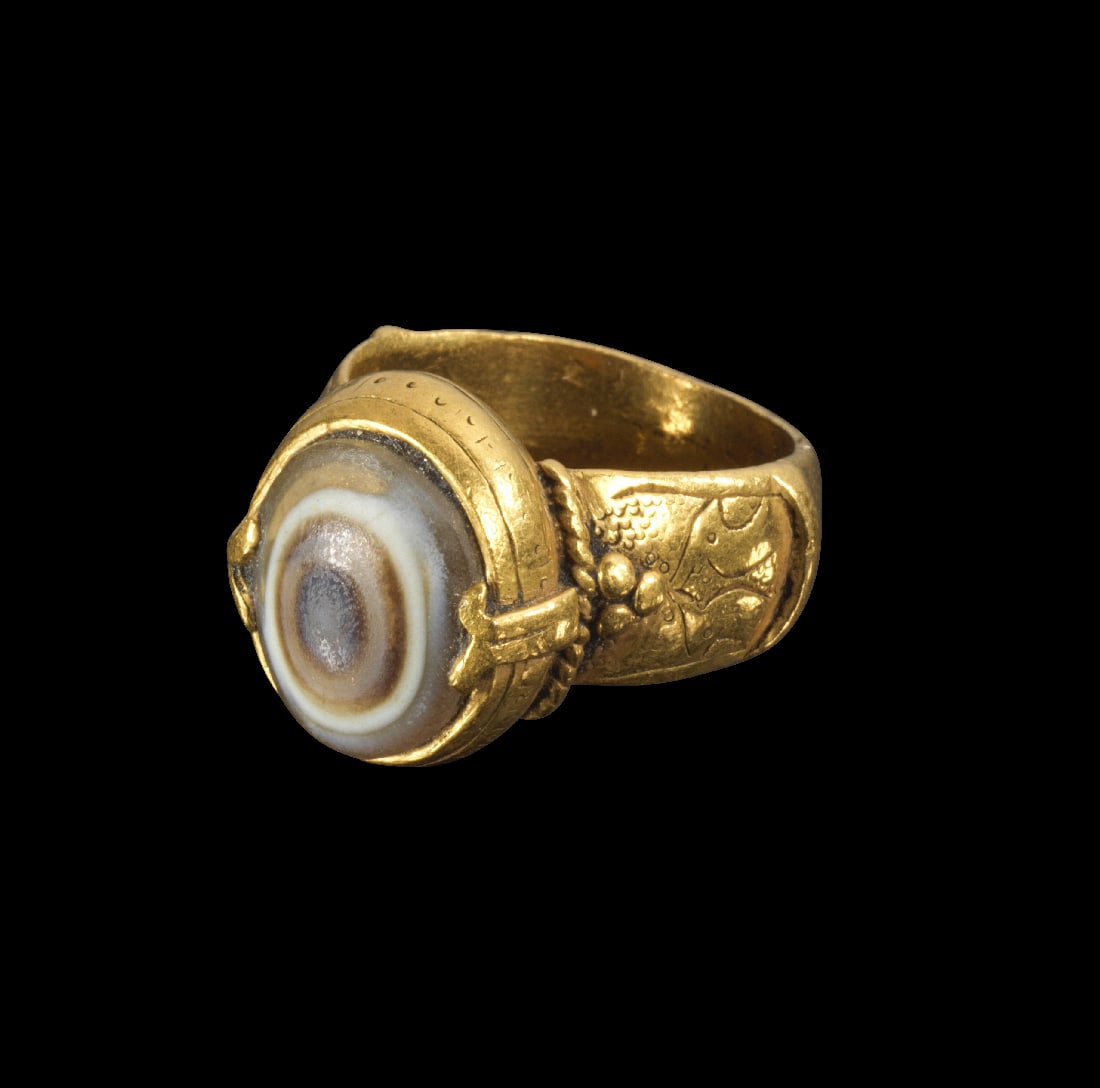 Goldring mit Lagenachat.: Goldring mit Lagenachat. Islamisch, 16. /17. Jh. 7,99g, Ringgroesse 53. Nach oben breiter werdende Schiene, die im oberen Bereich zwei symmetrische, gravierte Papageienkoepfe und am uebergang zur