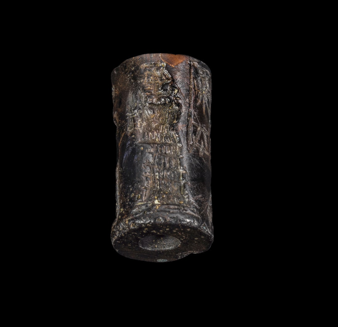 Rollsiegel mit Sonnengott.: Rollsiegel mit Sonnengott. Altbabylonisch, ca. 2003 - 1595 v. Chr. H 2,4cm, ? 1,3cm. Haematit. Sonnengott Schamasch mit Saege in der Linken, den Fuss auf einen Berg gesetzt. Ihm gegenueber der