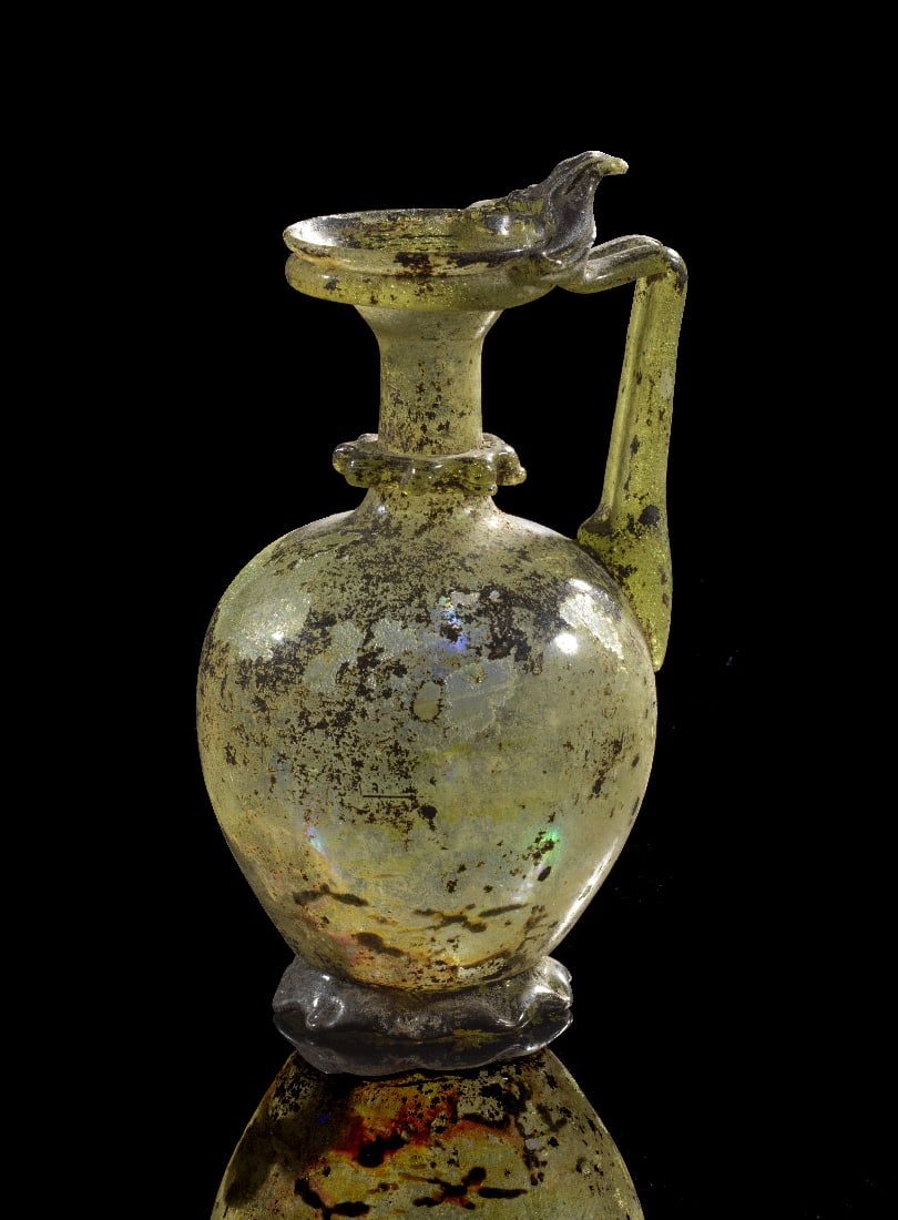 Krug mit gezacktem Standring und ausgepraegter Daumenrast.: Krug mit gezacktem Standring und ausgepraegter Daumenrast. oestliches Mittelmeer, roemische Zeit, 4. Jh. n. Chr. H 16,5cm. Hellgruenes, transluzides Glas. Der eifoermige Korpus sitzt auf einem