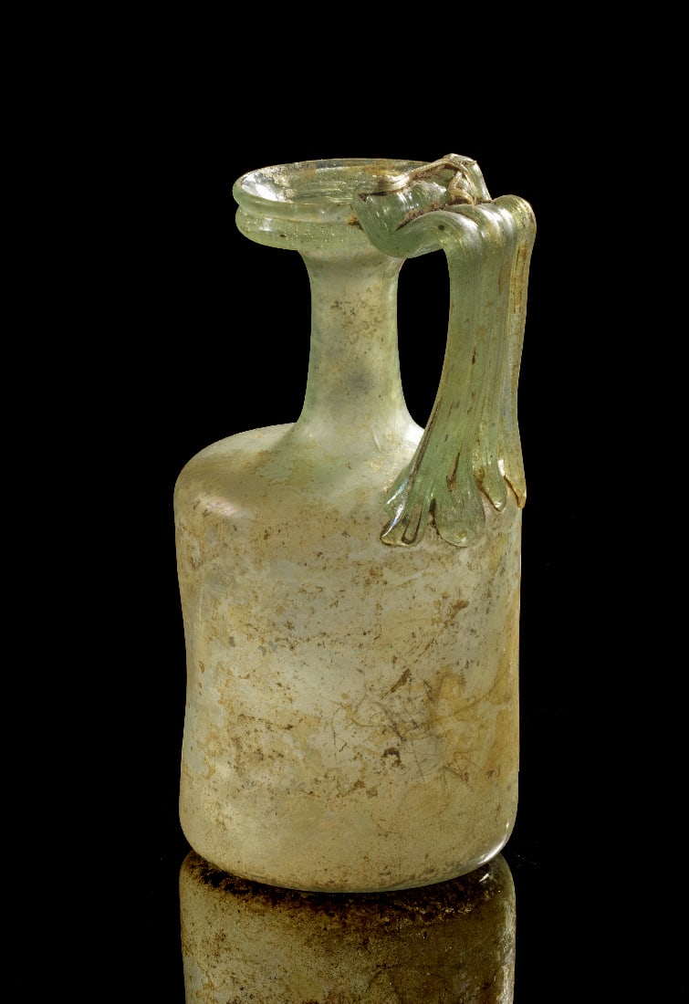 Spaetroemischer Henkelkrug mit appliziertem Fadenhenkel und Ritzverzierung.: Spaetroemischer Henkelkrug mit appliziertem Fadenhenkel und Ritzverzierung. Roemisch, 3. - 4. Jh. n. Chr. H 15cm. Freigeblasenes Glas von urspruenglich hellgruener Toenung. Zylindrischer, leicht