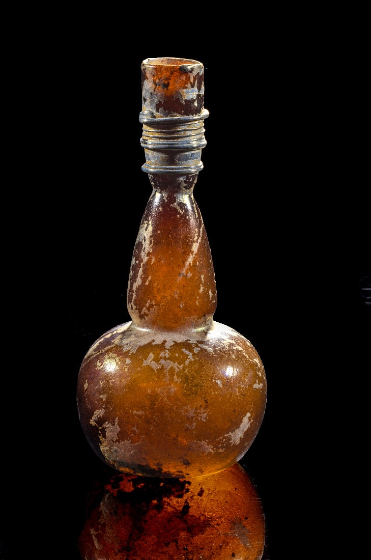 Elegante spaetantike Glasflasche mit kugeligem Korpus und fadenverziertem Hals.: Elegante spaetantike Glasflasche mit kugeligem Korpus und fadenverziertem Hals. oestliches Mittelmeer, spaetantike Zeit, 5. - 6. Jahrhundert n. Chr. H 17,3cm. Transluzides Glas in warmem Bernsteinton