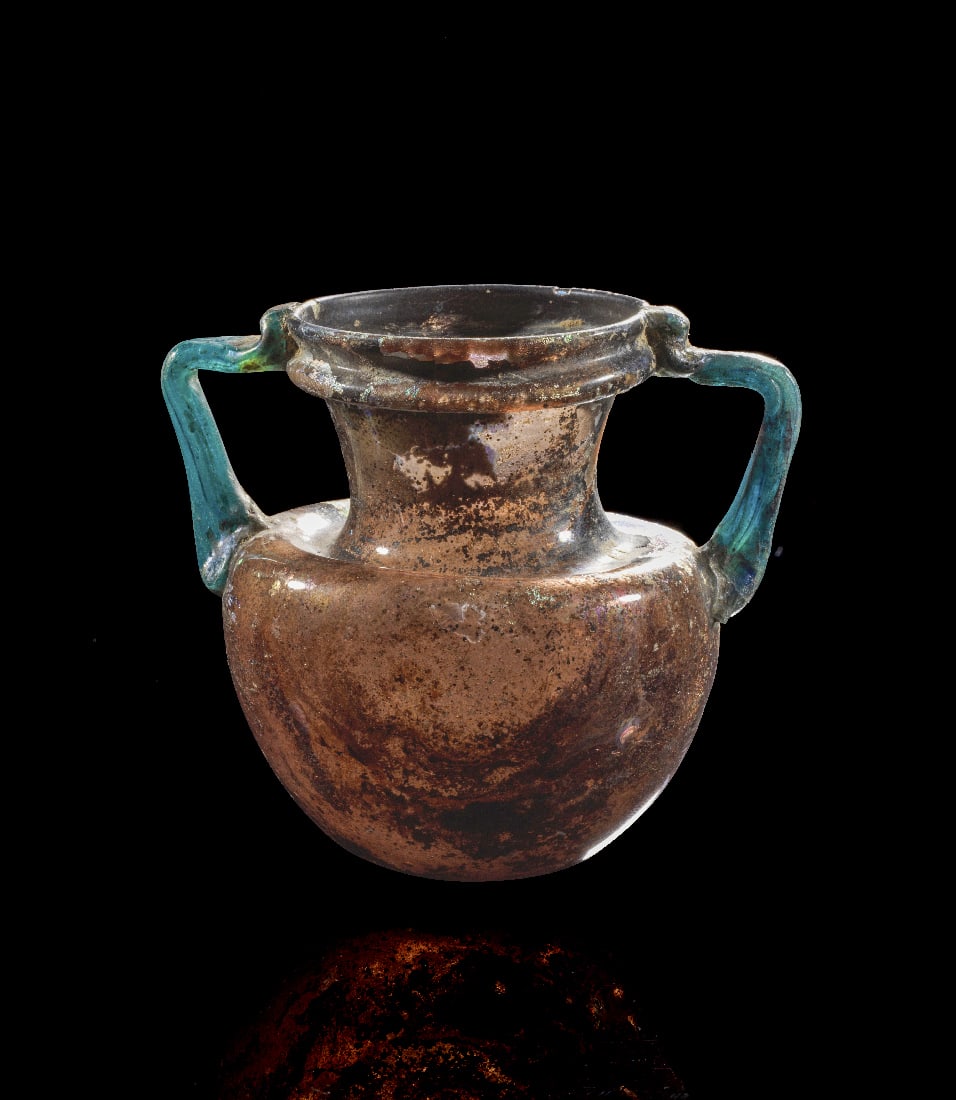 Roemischer Doppelhenkelkrug (Amphoriskos).: Roemischer Doppelhenkelkrug (Amphoriskos). Roemische Kaiserzeit, 2. - 3. Jh. n. Chr. H 10cm. Glas von urspruenglich hellgruenlicher bis schwach aquamarinfarbener Toenung, heute dunkel verfaerbt. Frei 