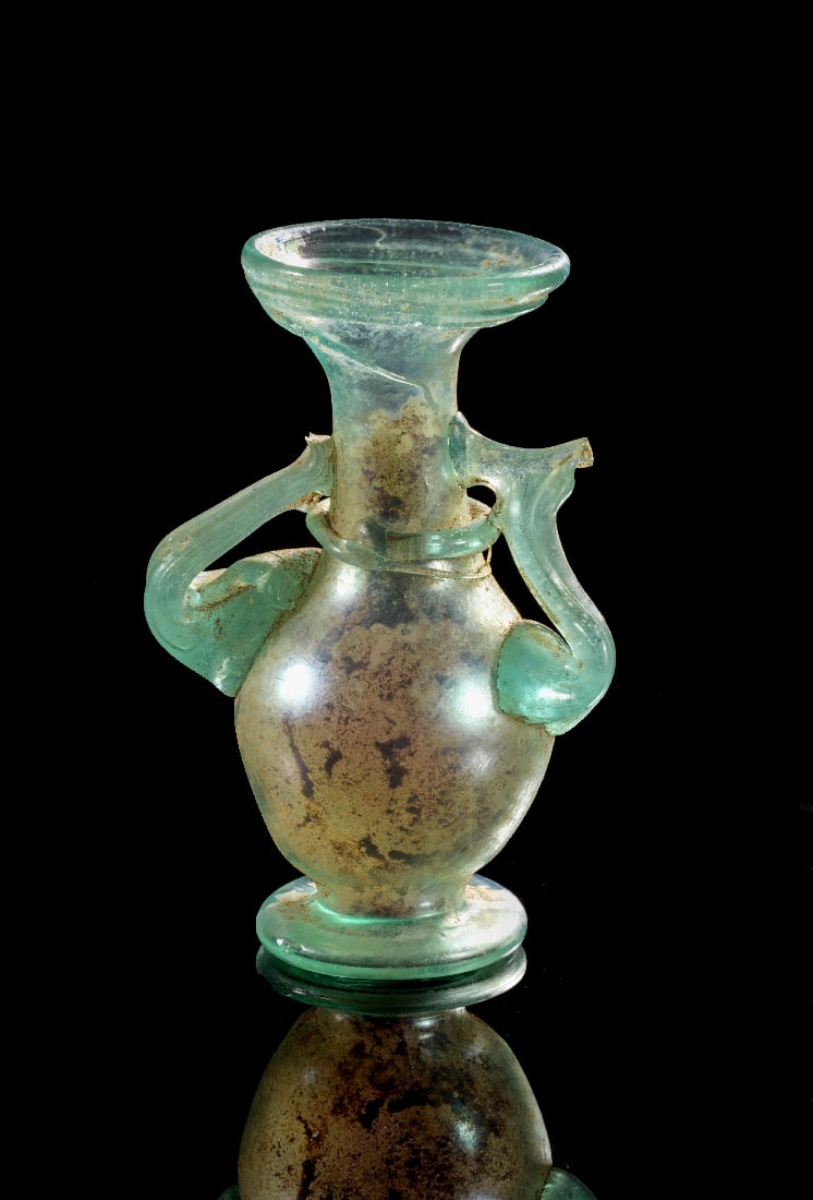 Roemisches Balsamarium mit applizierten oesen und irisierender Patina.: Roemisches Balsamarium mit applizierten oesen und irisierender Patina. Roemisch, 3. - 4. Jh. n. Chr. H 9cm. Freigeblasenes Glas von blass blaugruener, leicht aquamarinfarbener Toenung mit