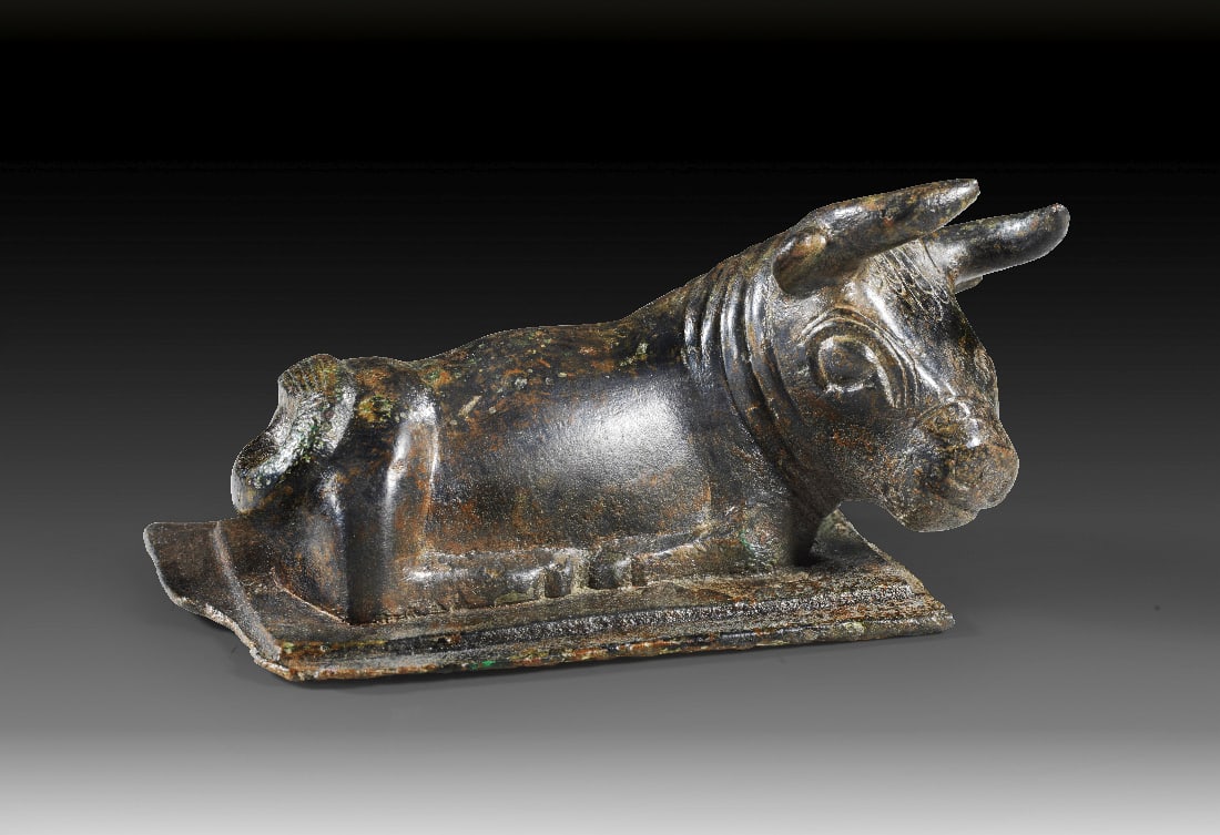 Liegender Stier aus Bronze.: Liegender Stier aus Bronze. Westasiatisch, 1. Haelfte 1. Jt. v. Chr. L 11,5cm, B 6,2cm. Bronzevollguss, Details in Kaltarbeit. Auf flacher, rechteckiger, abgetreppter Basisplatte liegender Stier mit