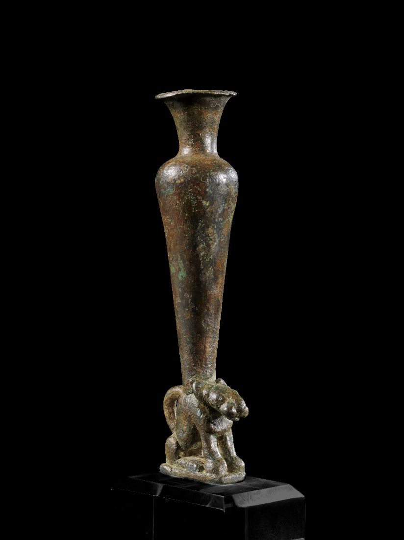 Kohl-Gefaess aus Bronze.: Kohl-Gefaess aus Bronze. Vorderasien, 2. Jt. v. Chr. H 12cm. Schlankes Gefaess mit kurzem Hals und ausladender Muendung auf einem sitzenden Panther, dessen Schwanz wie zu einem Henkel aufgebogen ist.