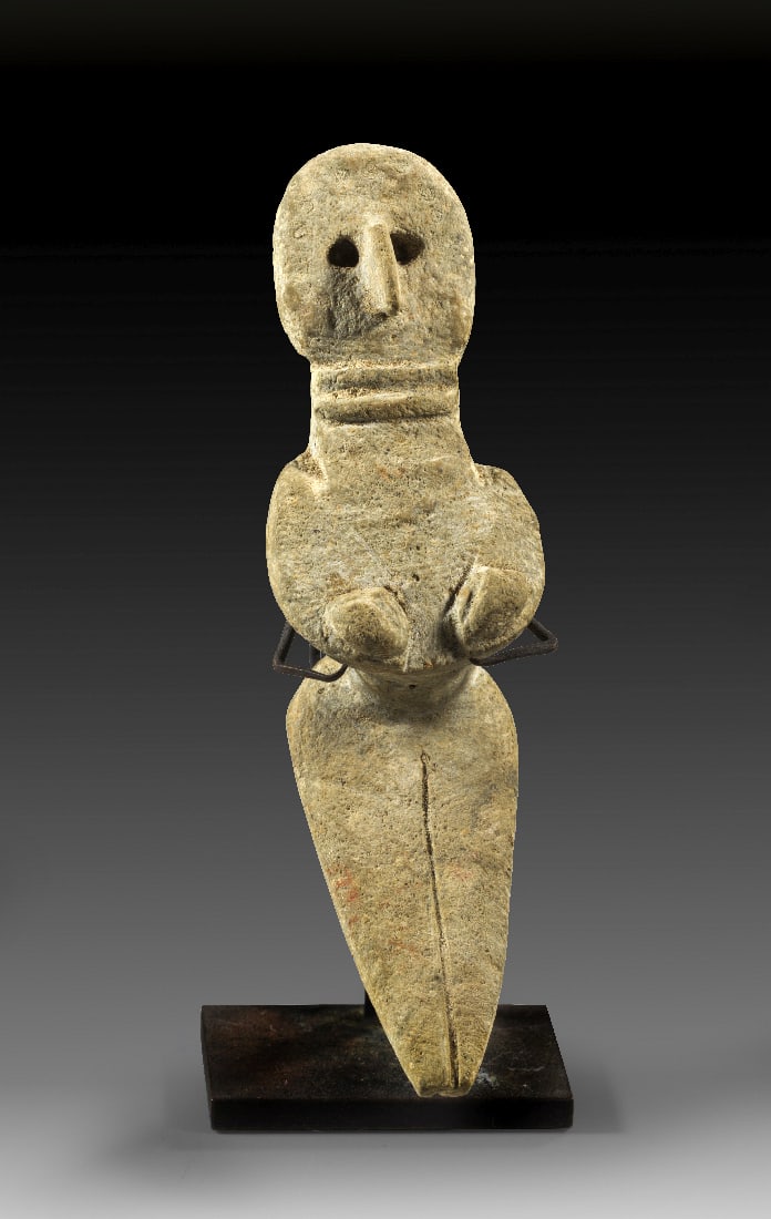 Weibliches Idol.: Weibliches Idol. Indus-Tal-Kultur, ca. 3. Jt. v. Chr. L 11cm. Aus beigen Ton. Stilisierte, weibliche, nackte Figur, die sitzend ihre Brueste umfasst. Flacher Kopf mit Vogelnase und vertieften Augen,