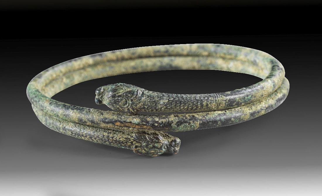 Urartaeischer Bronzearmreif.: Urartaeischer Bronzearmreif. 7. - 6. Jh. v. Chr. ? 8,6cm. Doppelter Reif, der in Koepfen von schlangenaehnlichen Fabelwesen endet. Mit Zertifikat der Galerie Puhze von 1977. Sehr feine Arbeit! Gruene 