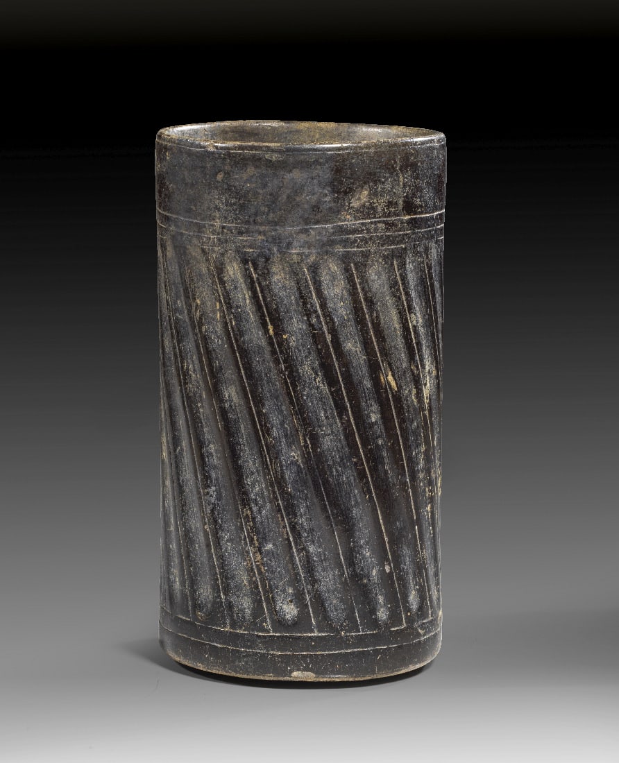 Grosser, eleganter Becher mit Kanneluren.: Grosser, eleganter Becher mit Kanneluren. Maya-Kultur, Klassische Periode, ca. 550 - 950 n. Chr. H 21,5cm ? 10.5cm. Zylindrischer, schwarzbraun glasierter Becher mit einem umlaufenden Fries leicht sch