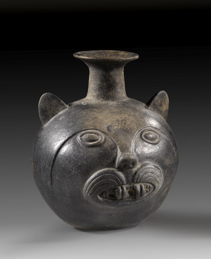 Gefaess.: Gefaess. Chimu, ca. 1300 n. Chr. H 19,5cm. Grauer Ton mit schwarzem ueberzug. In Form des Kopfes einer Raubkatze, vermutlich eines Jaguars, mit gebleckten Reisszaehnen. Mit TL-Gutachten! Intakt.