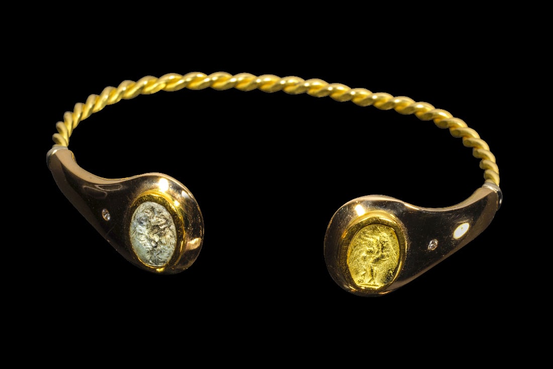 Armreif aus Gelbgold mit Achat-Gemme.: Armreif aus Gelbgold mit Achat-Gemme. Gemme: 1. - 2. Jh. n. Chr., Goldguss: 2019. 31,59g, ? 7,5cm. Armreif aus tordiertem Golddraht mit offenem Enden. An einem Ende eine gefasste Achat-Gemme. Darauf L