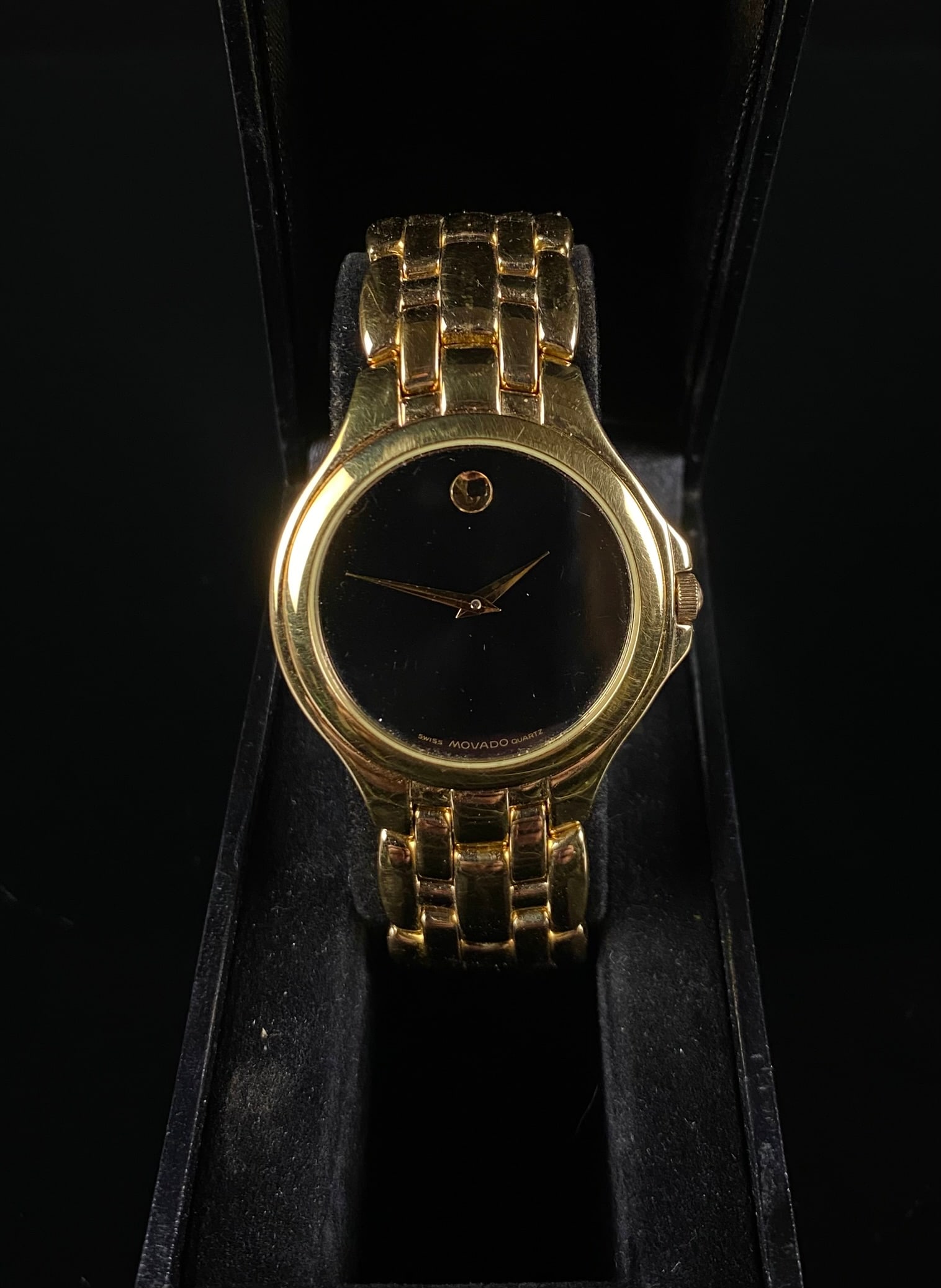 Ladies Movado Gold-Tone and Stainless Steel Museum Dial Quartz Wristwatch, Model 88.E4.9872: A Movado gold-tone and stainless steel quartz wristwatch featuring the iconic black Museum Dial. The dial presents a single gold-tone dot at the 12 o'clock position and two matching dauphine hands. Th