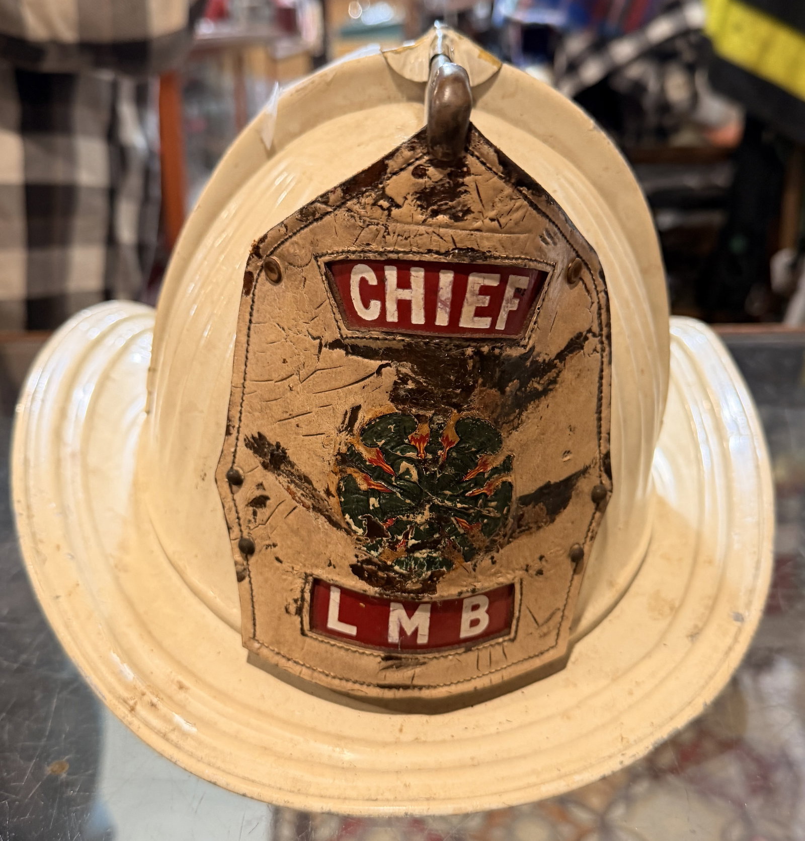 Cairns & Brother Senator Fire Chief Helmet with Leather Front Shield: Produced 1947-66, A vintage American-style firefighter's helmet by Cairns & Brother. Constructed with an off-white painted Tin shell and a prominent, worn leather front shield. The shield features "CH