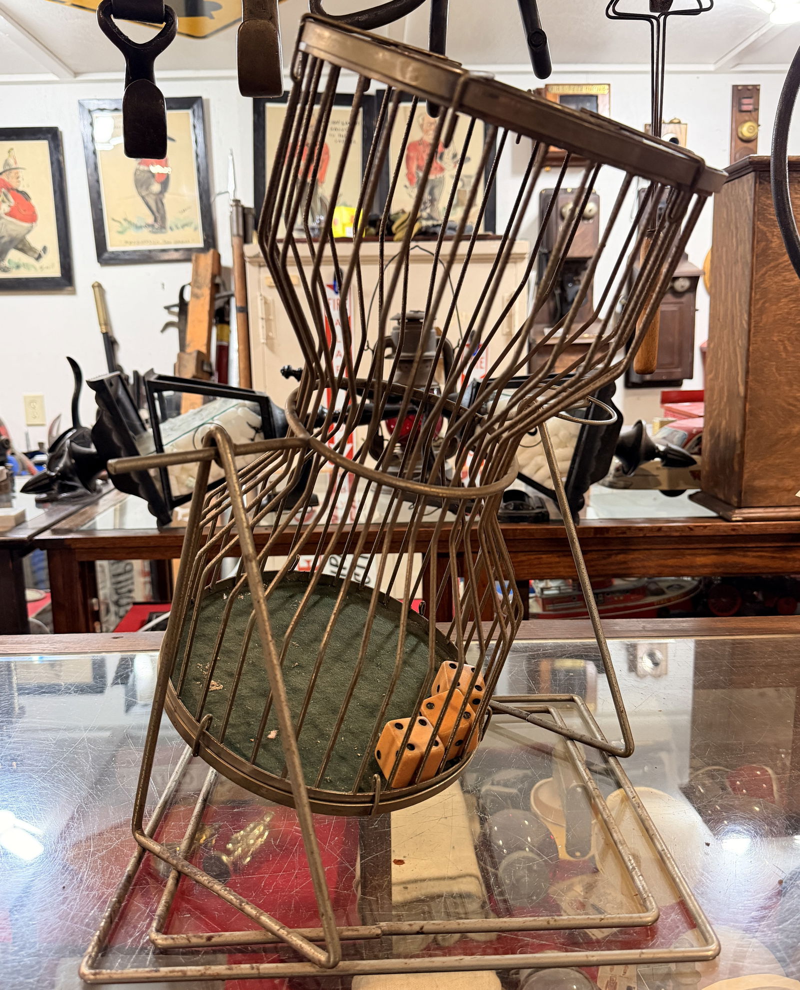 Vintage Chuck-A-Luck Caged Dice Game: A vintage Chuck-A-Luck caged dice game From a Fire House. Constructed from patinated brass-toned metal wire, this hourglass-shaped rotary game cage is mounted on a sturdy wire frame base, designed to