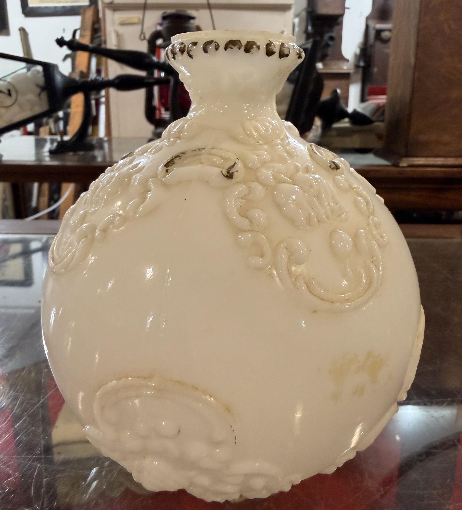 Antique Victorian White Milk Glass Embossed Rococo-Revival Fire Barber Bottle: An antique Victorian white milk glass embossed barber bottle. This opaque white milk glass decorative vessel features a globular body with a short, flaring neck and a molded, scalloped rim. The