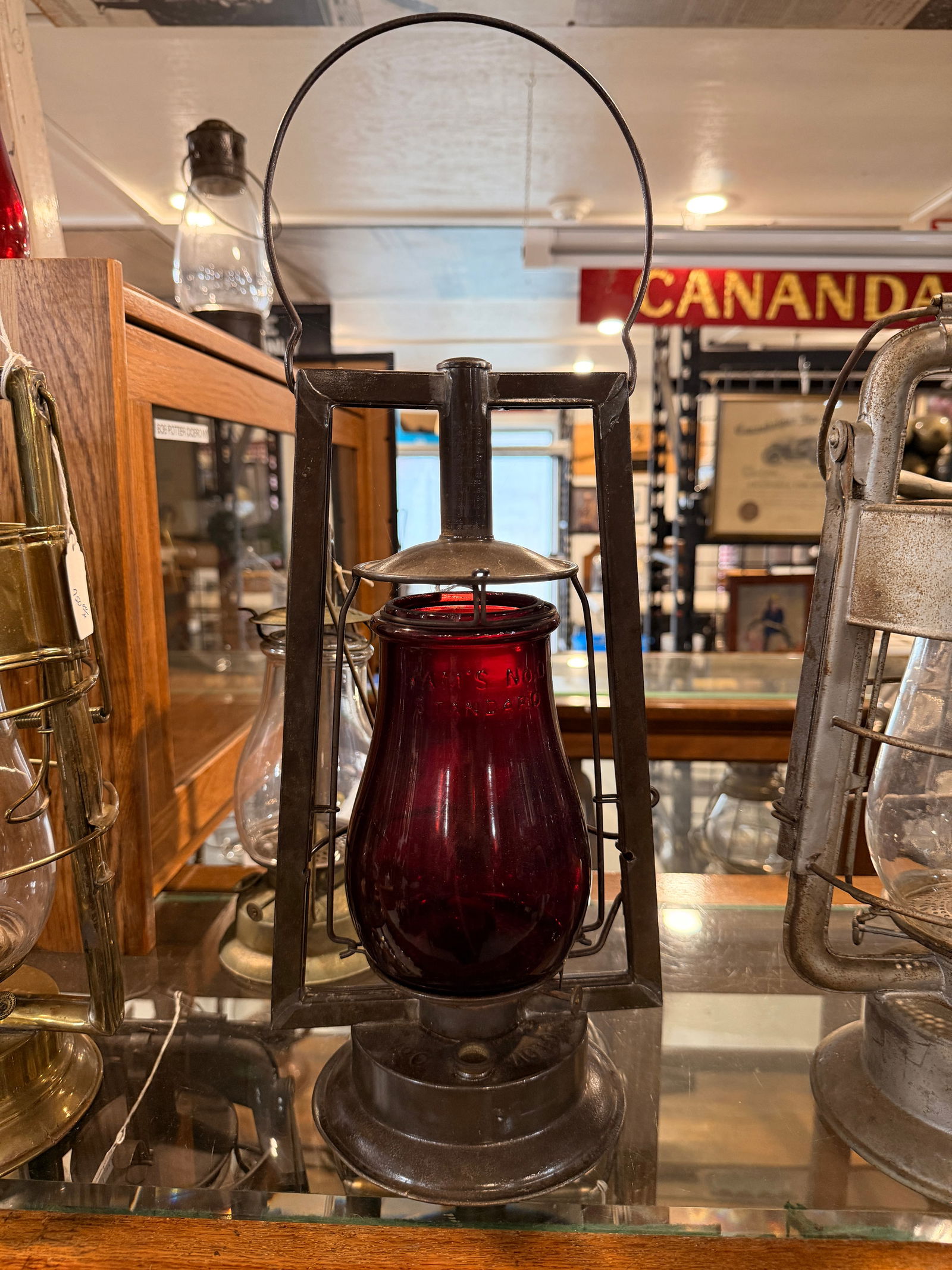 Steam Gauge and Lantern Co. Syracuse No. ) Railway Lantern, Late 19th Century: Steam Gauge and Lantern Co. No 0. Standard railway-style lantern, featuring a dark red glass globe encased within a sturdy, darkened metal frame with a fixed carrying handle and a metal fuel fount at