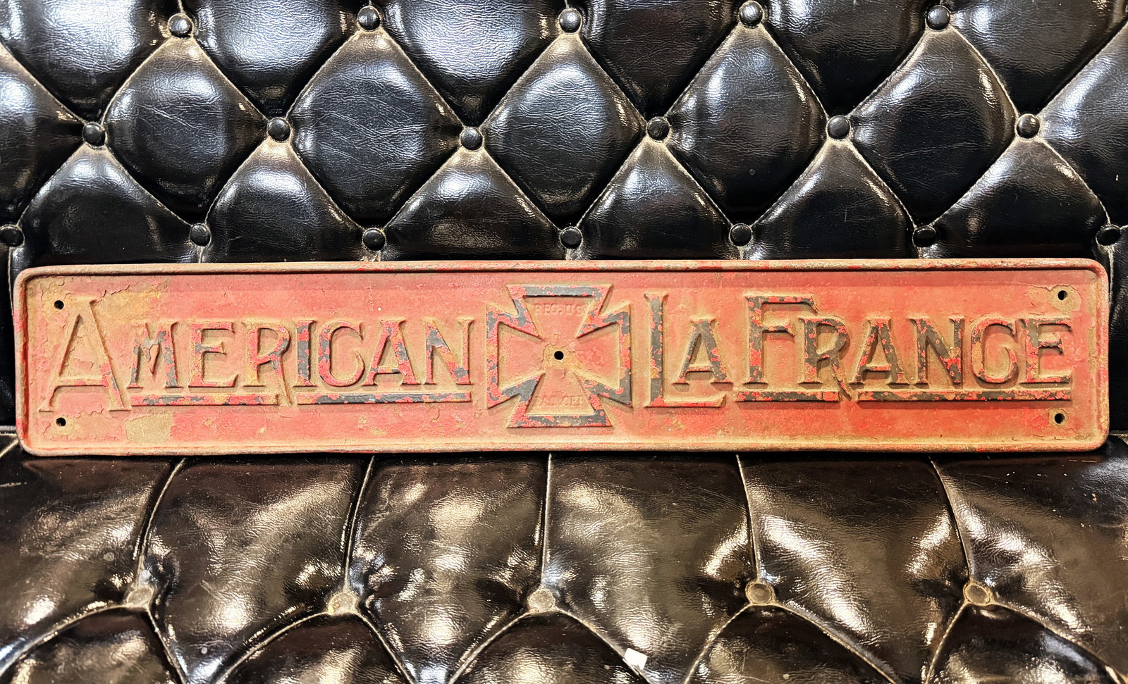 1910's 20's American LaFrance Cast Iron Embossed Plaque: A American LaFrance cast iron embossed plaque, rectangular in form, featuring raised lettering that spells "AMERICAN" on the left and "LA FRANCE" on the right. These words are separated by a central M
