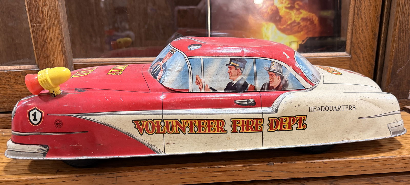 Louis Marx Tin Lithographed Friction Volunteer Fire Dept Chief Car: A Louis Marx tin lithographed friction-driven 'Volunteer Fire Dept Chief' car. The toy features a two-tone red and off-white body with mid-century American car styling, including prominent fins and a