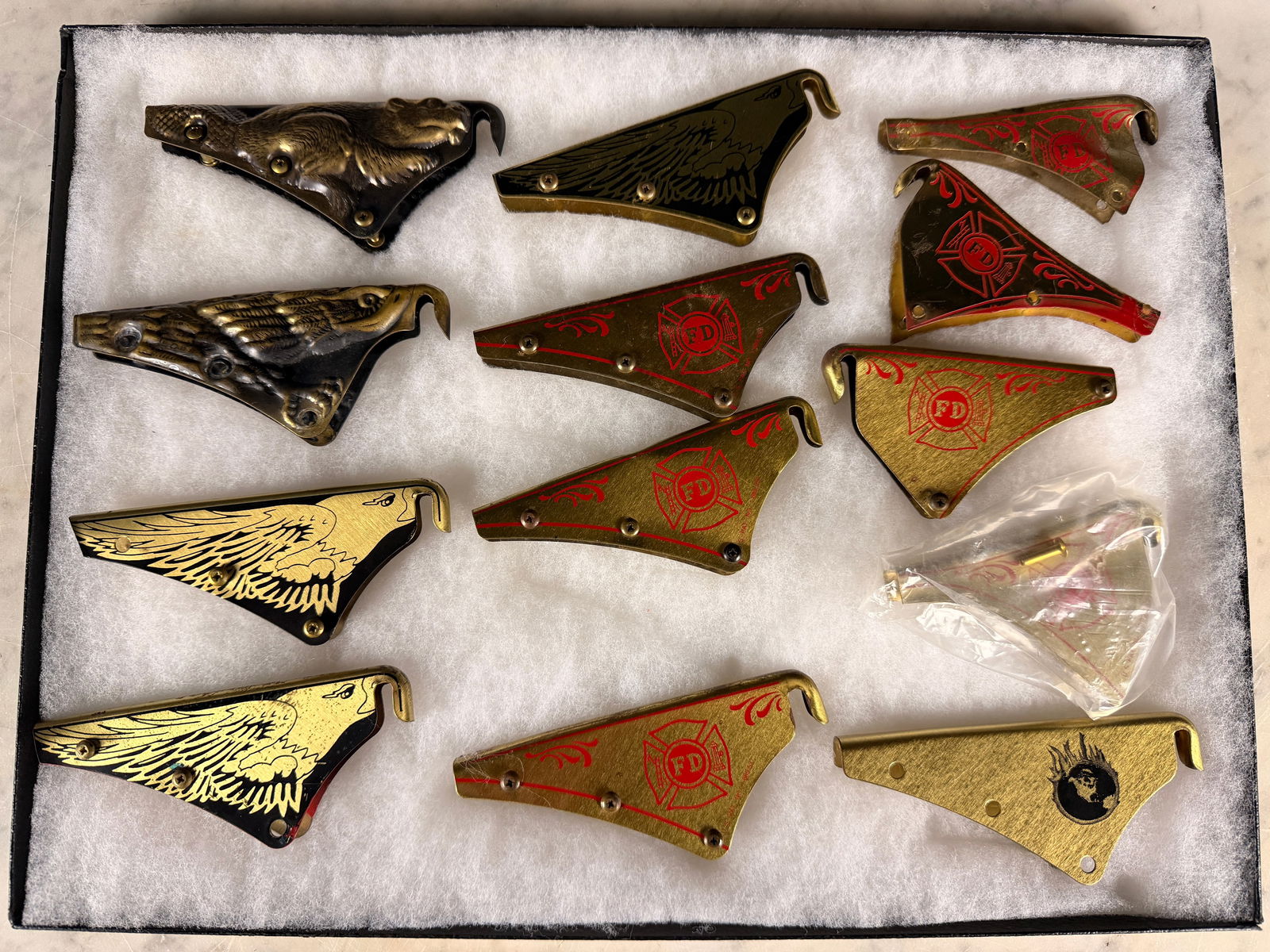 A Collection of MSA Cairns Fire Helmet Front Holders and Eagles: A collection of helmet shields or ornamental brackets, identified through market consensus as MSA Cairns Fire Helmet Front Holders, designed to secure the leather front piece (not included) to a fire