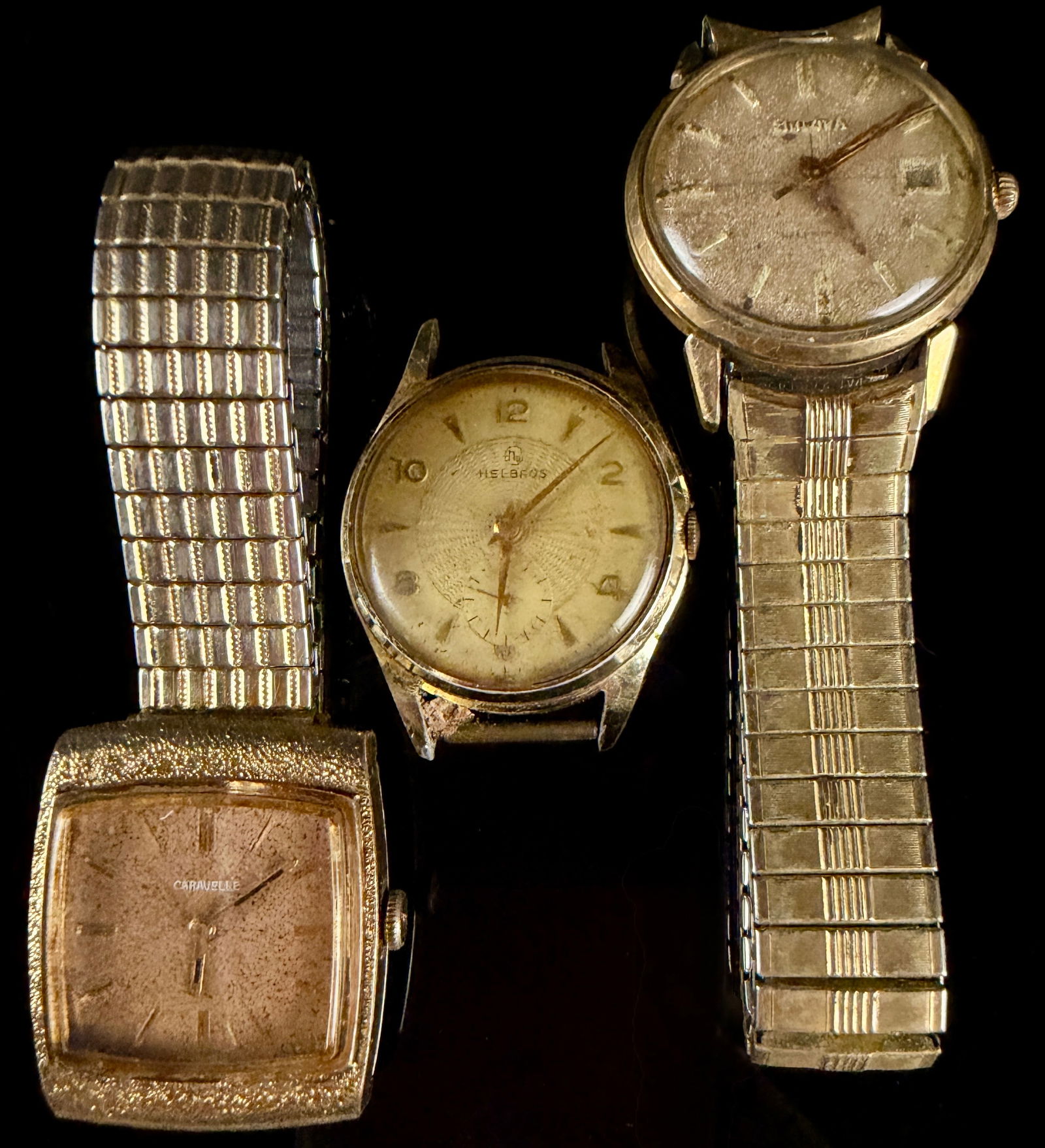 Mixed Lot of Three Vintage Men's Wristwatches Caravelle Helbros Bulova: A collection of three vintage mechanical-style wristwatches sold as a lot for restoration or parts. The lot includes a Caravelle watch, a Helbros watch head, and a Bulova watch. The Caravelle features