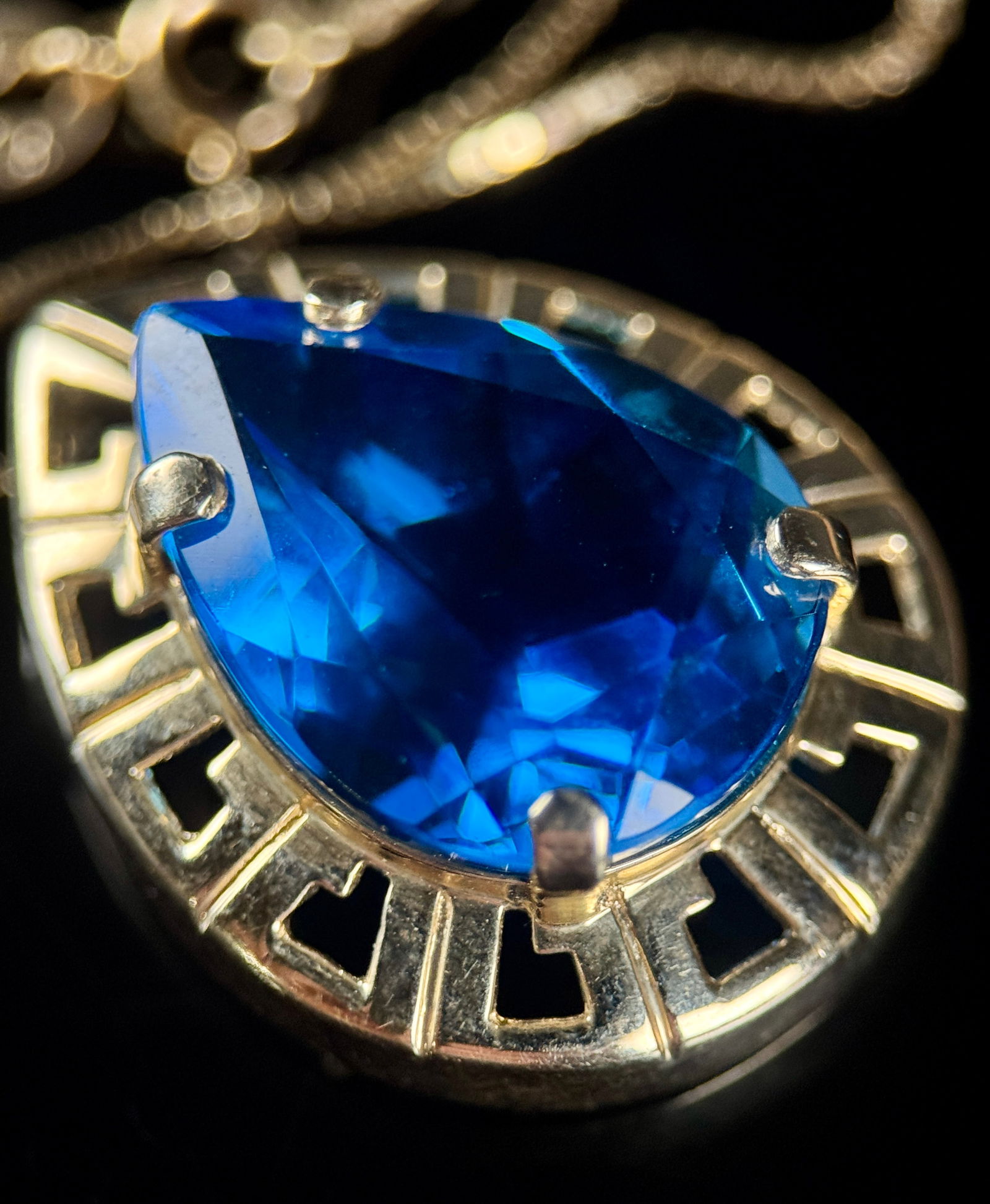 14K Gold Box Chain Necklace with Pear-Cut Blue Simulant Pendant: A contemporary necklace featuring a 14K yellow gold box chain secured by a spring ring clasp. The chain is affixed with a tag plate visibly marked 14K, denoting the gold purity. The pendant features a