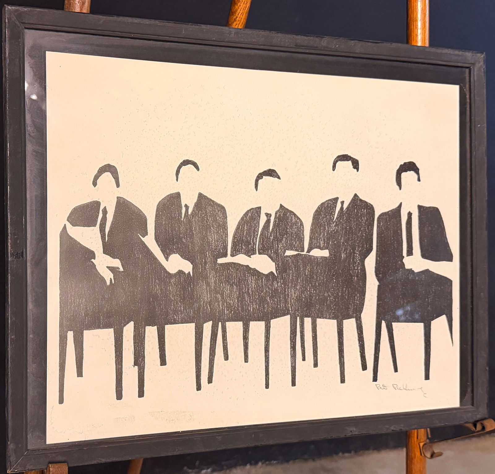 Pat Pickering, Five Men Seated Block Print: A framed monochromatic block print by artist Pat Pickering titled Five Men Seated. The work features a minimalist, high-contrast graphic depiction of five male figures in suits seated at a table. The