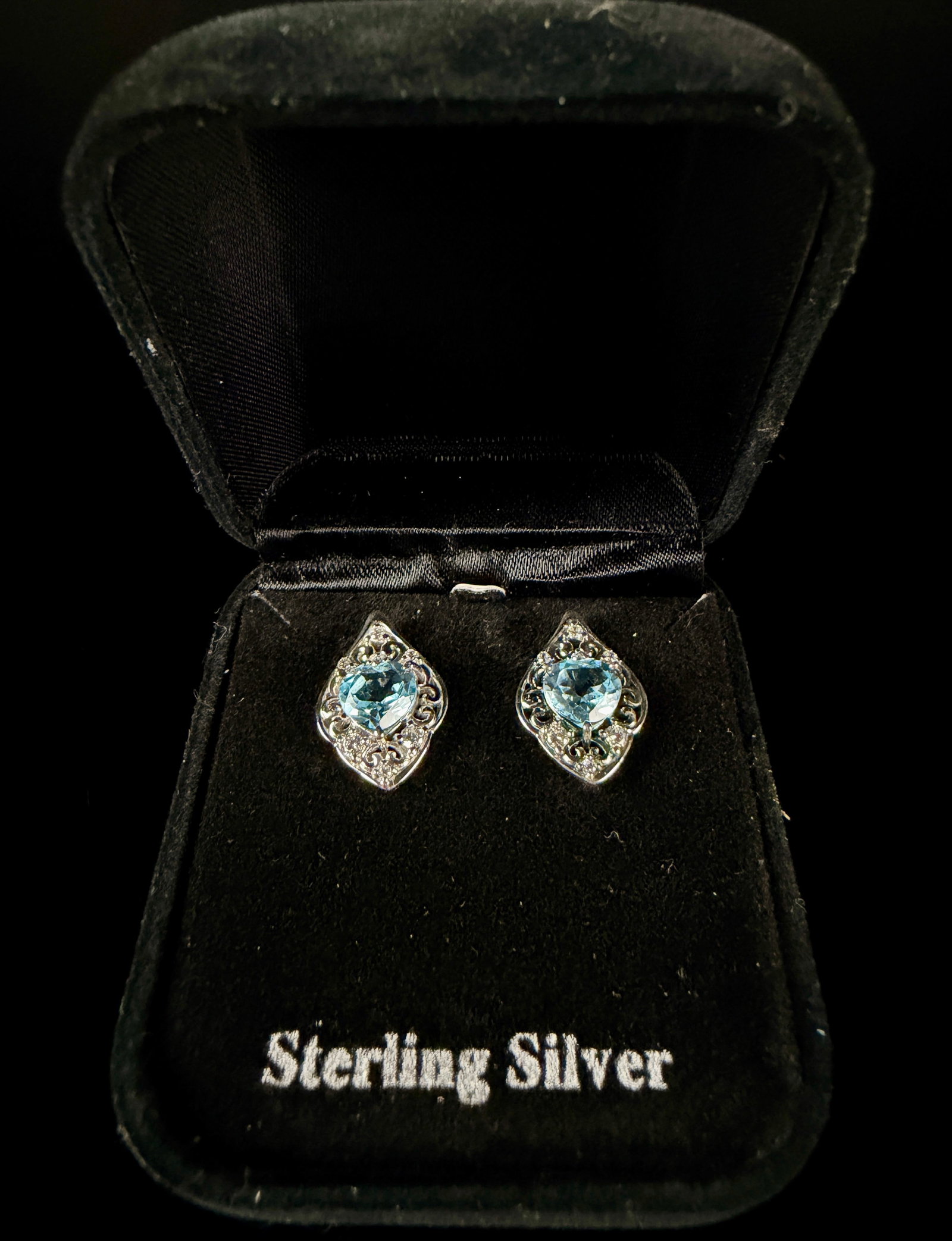A Pair of Sterling Silver and Blue Topaz Heart-Cut Filigree Stud Earrings: This lot consists of a pair of sterling silver stud earrings, each featuring a central heart-cut light blue gemstone. Based on market research of visually identical items, the stones are identified as