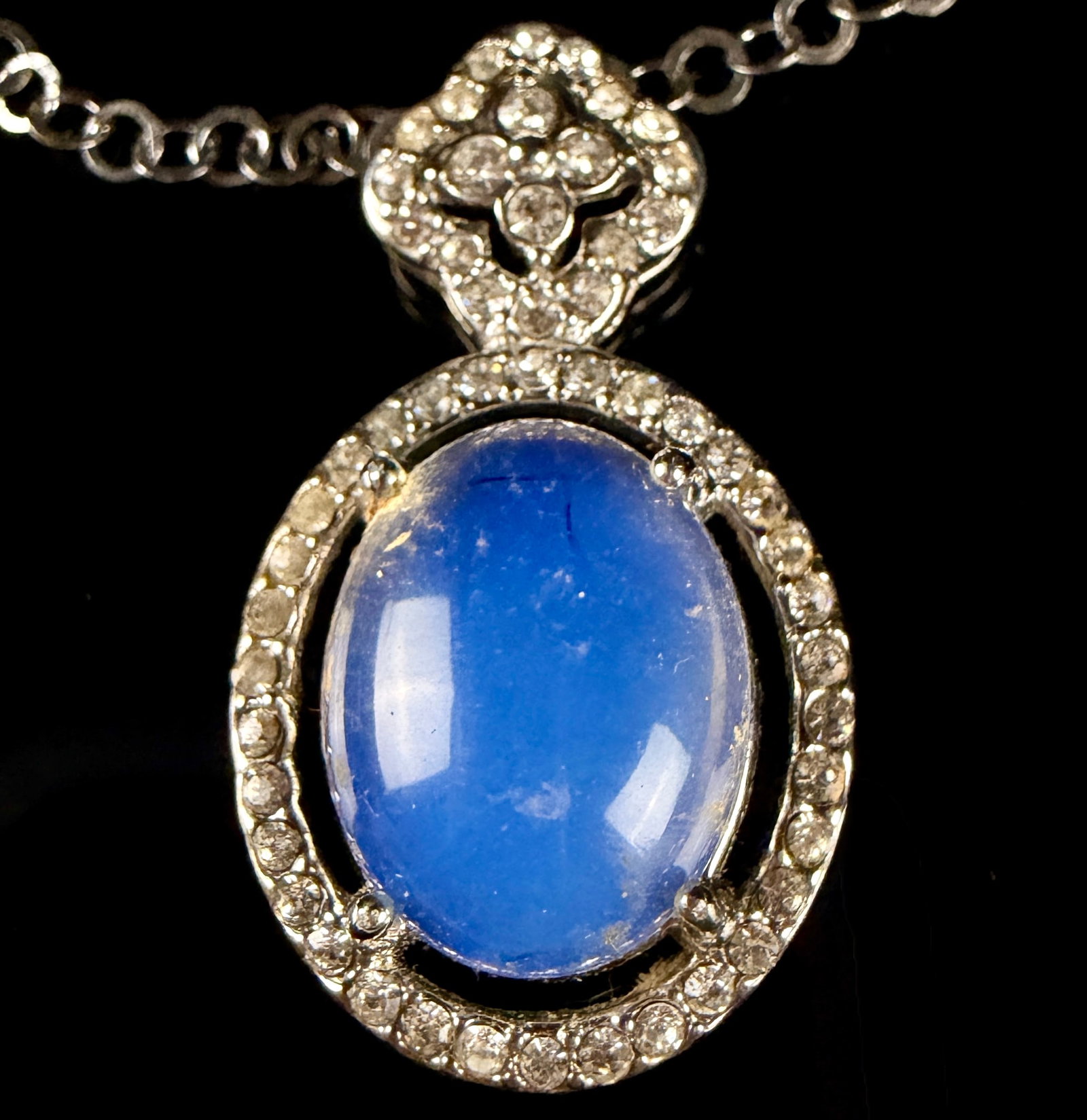 Sterling Silver and Blue Opalescent Cabochon Pendant Necklace: This necklace features a sterling silver pendant set with a large, oval cabochon of a translucent blue stone. The central stone exhibits opalescent qualities, displaying a color shift when backlit. Th