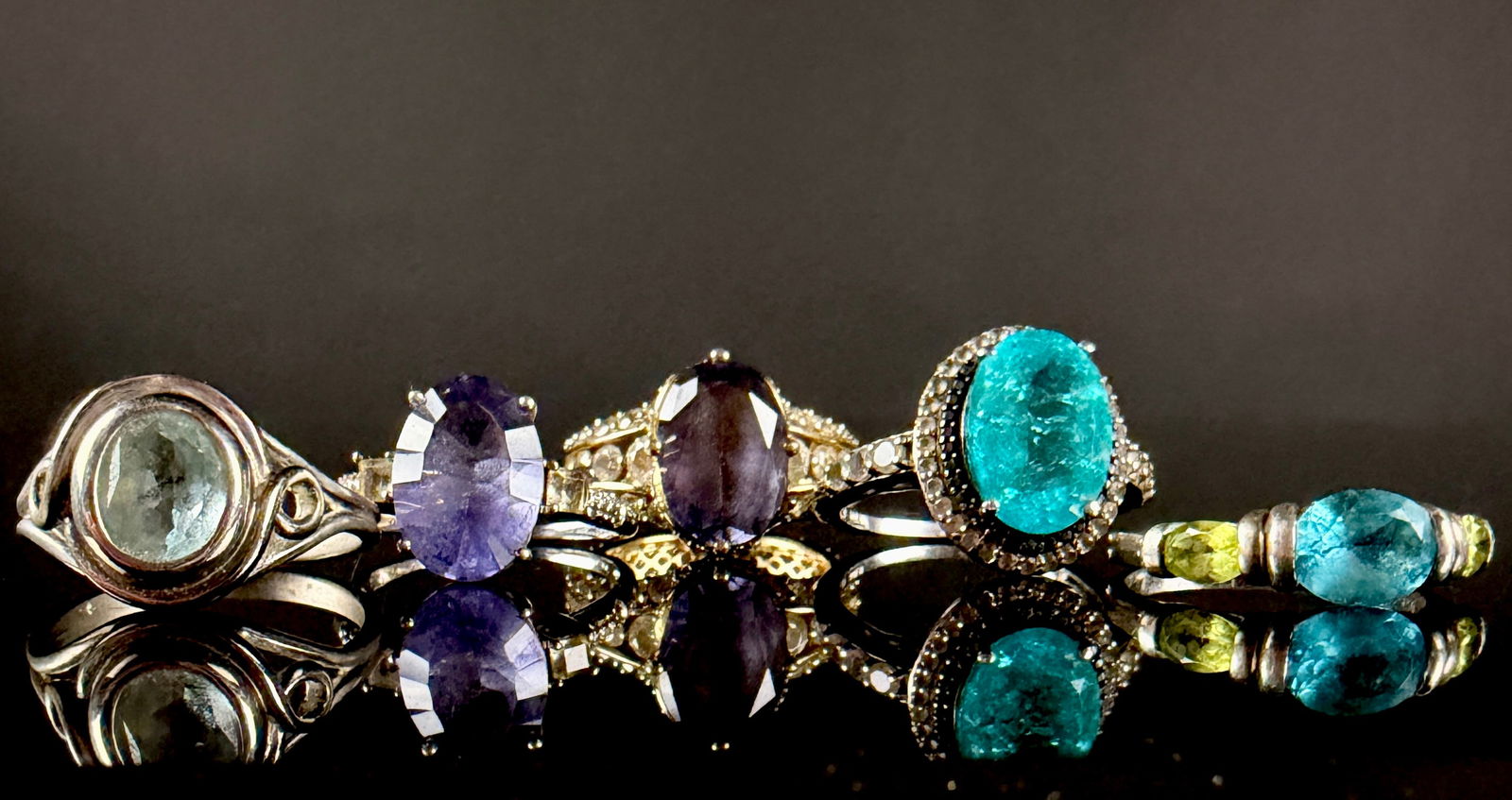 A Collection of Sterling Silver and Gemstone Rings: A collection of rings featuring sterling silver construction with both silver and gold-toned finishes. The group includes various styles such as halo, solitaire, and multi-stone settings. The primary