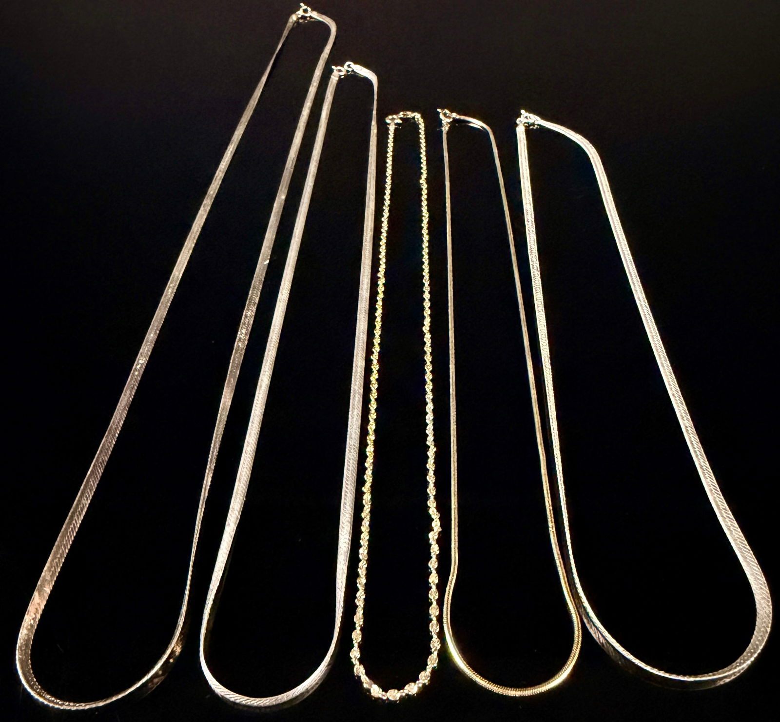 An Assortment of Rose, Yellow, and White Gold Plated Chains: An assortment of 18k rose, yellow, and white gold plated chains. These sterling silver necklaces feature flat herringbone and twisted rope chain styles in various widths and lengths. The collection in