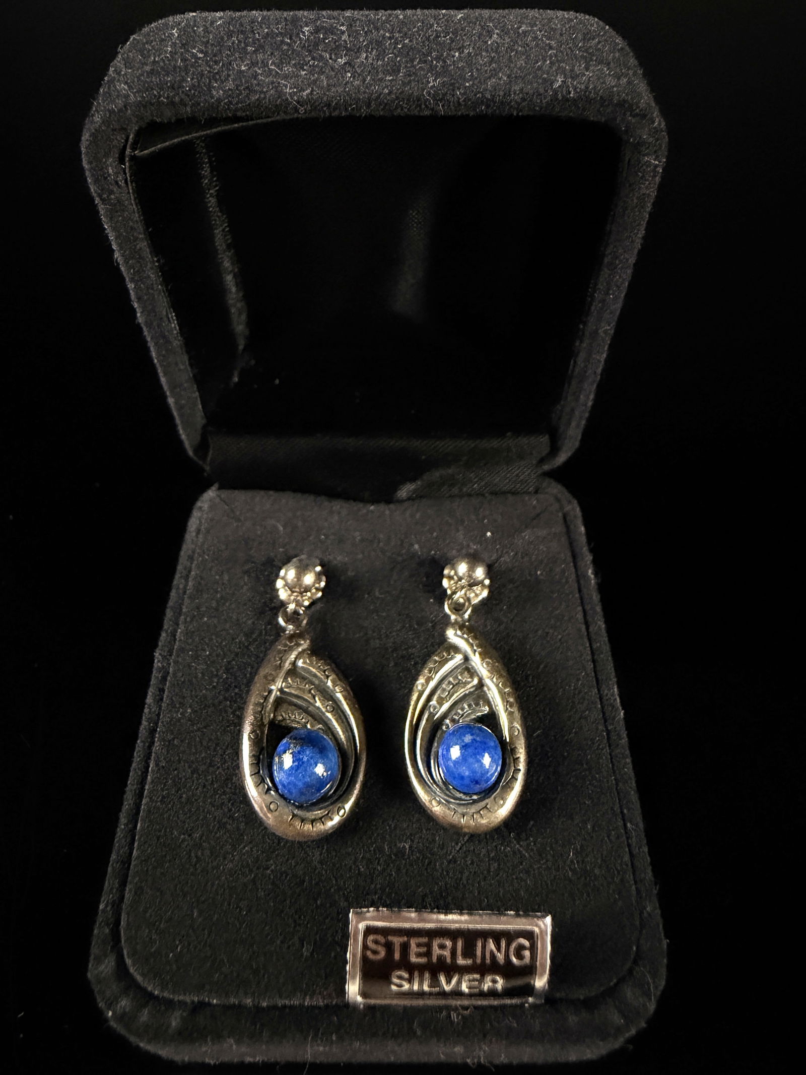 A Pair of Carolyn Pollack Relios Sterling Silver and Lapis Lazuli Drop Earrings: A pair of sterling silver and lapis lazuli drop earrings by Carolyn Pollack for Relios. Each earring features an openwork teardrop-shaped frame with tiered, swirling line details. At the base of each