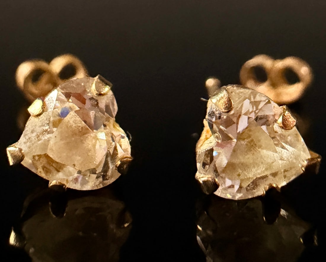 A Pair of 10k Yellow Gold and Heart-Cut Diamond Stud Earrings: A pair of stud earrings crafted in 10k yellow gold. Each earring is set with a prong-mounted, heart-cut colorless stone. The stones display visible internal inclusions and cloudiness, consistent with