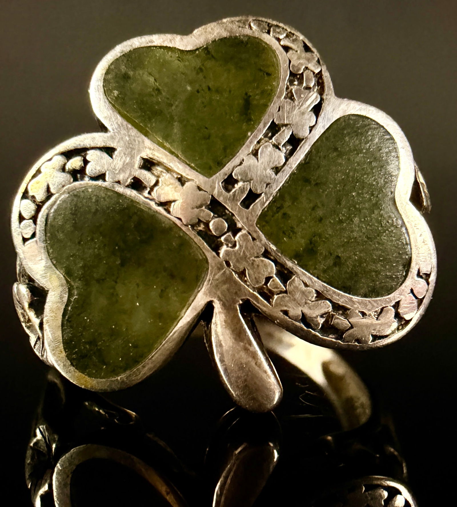 Irish Sterling Silver and Connemara Marble Shamrock Ring: An Irish sterling silver ring featuring a central three-leaf clover or shamrock motif. The design is composed of three heart-shaped sections inlaid with polished green Connemara marble. The silver set