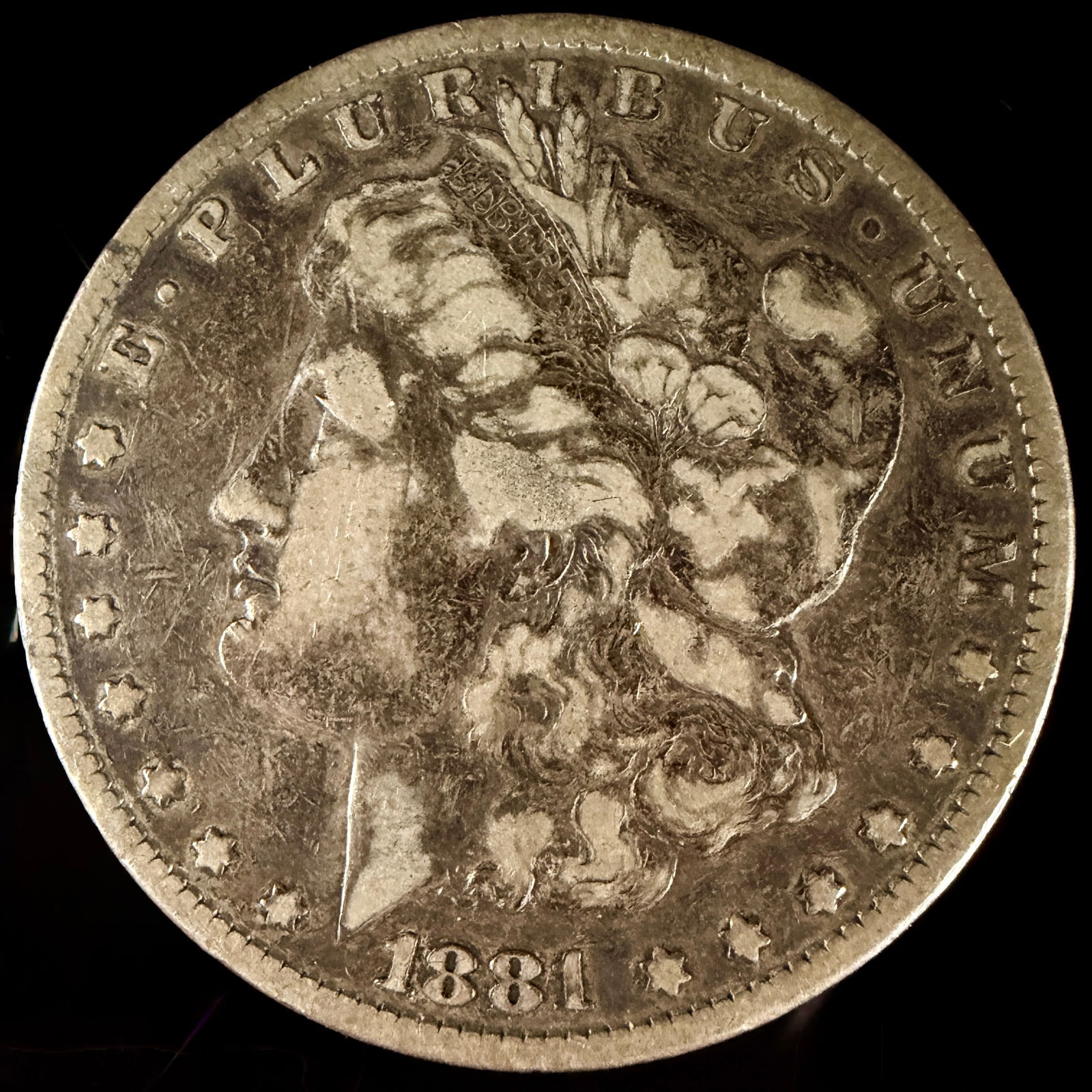 1881 Morgan Silver Dollar: This 1881 United States Morgan silver dollar features the George T. Morgan design. The obverse depicts a profile portrait of Liberty with the inscription E PLURIBUS UNUM, thirteen stars, and the date