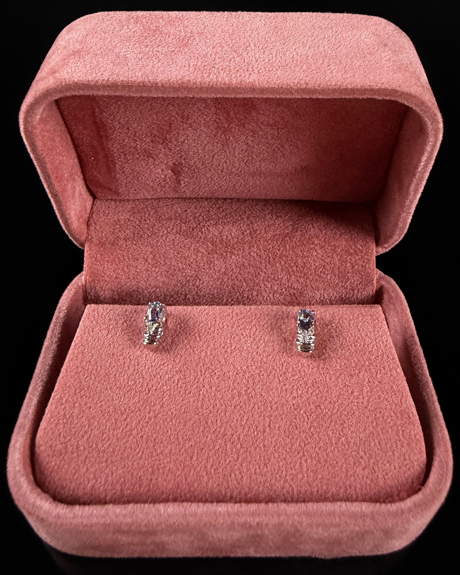 A Pair of 10K White Gold and Created Alexandrite Stud Earrings: This pair of stud earrings is constructed from 10K white gold. Each earring features a prong-set oval-cut created alexandrite gemstone displaying a purple-blue hue, positioned above a tiered arrangeme