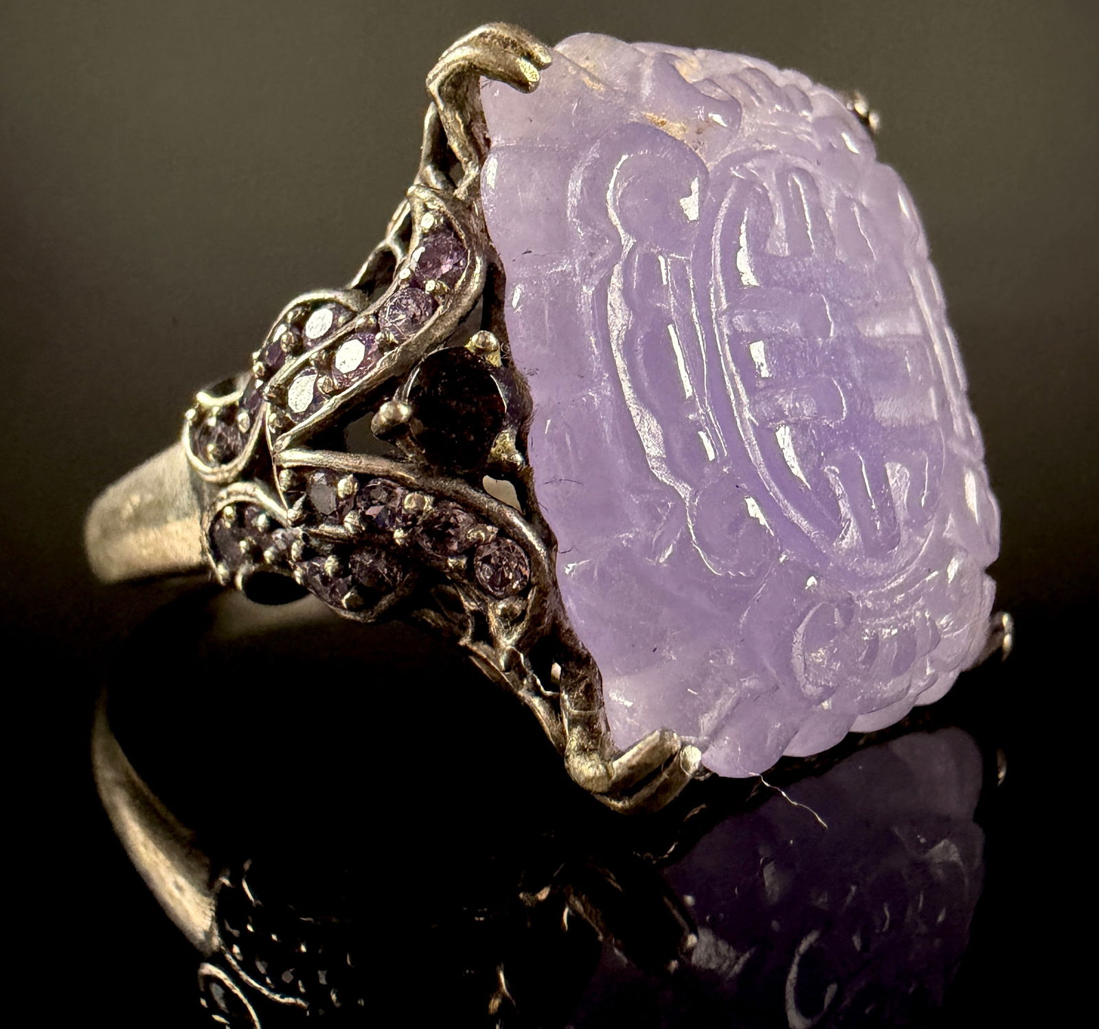Vintage Chinese Carved Lavender Jadeite and Garnet Sterling Silver Ring: A vintage Chinese carved lavender jadeite and sterling silver ring. The piece features a prominent rectangular lavender jadeite gemstone carved with a traditional shou longevity character. The gemston