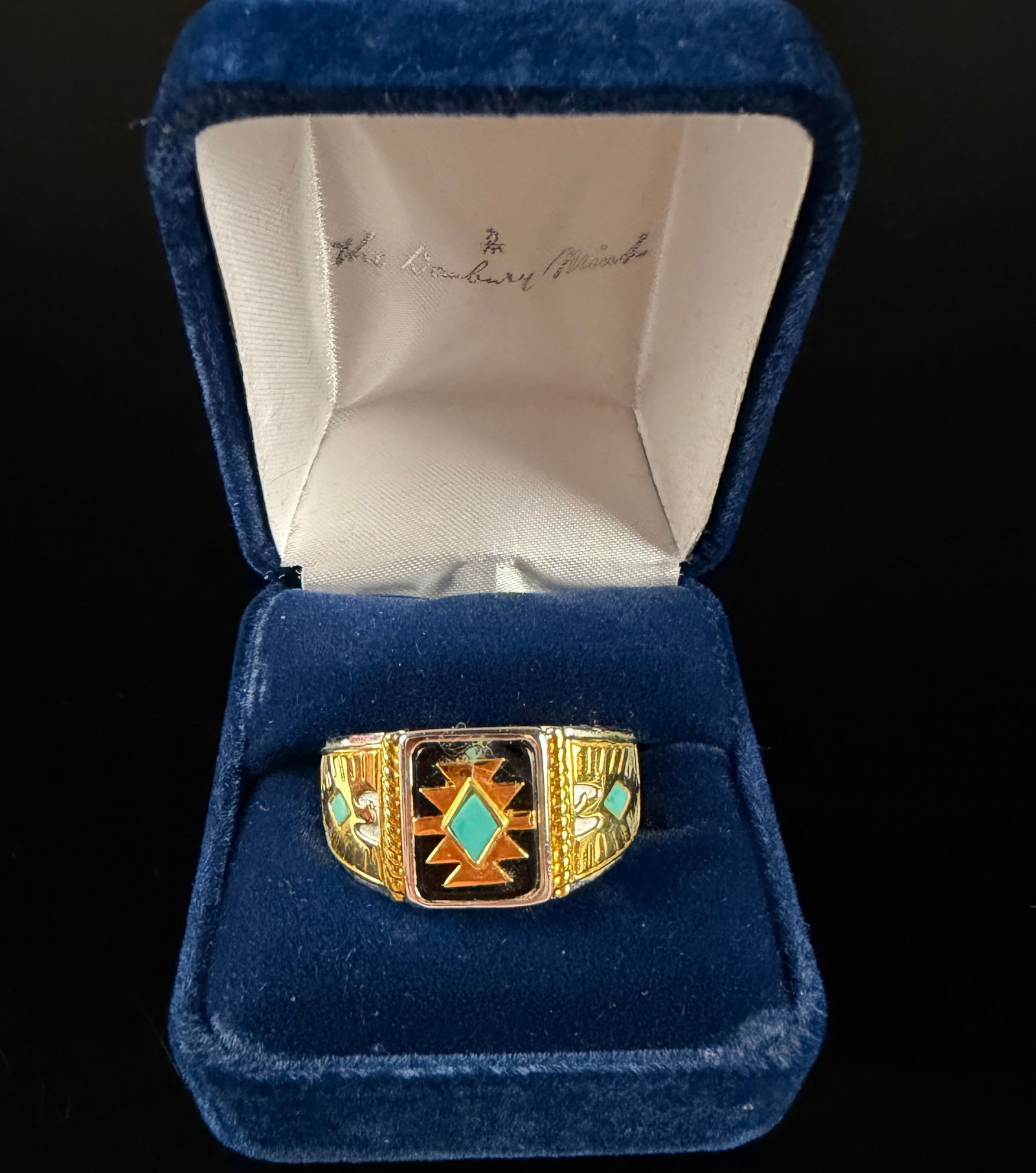 A Danbury Mint Men's Southwest Style Signet Ring: A men's signet-style ring produced by The Danbury Mint featuring a Southwest-inspired design. The ring is constructed with a bi-metal silver and gold-tone finish. The rectangular central face is set w