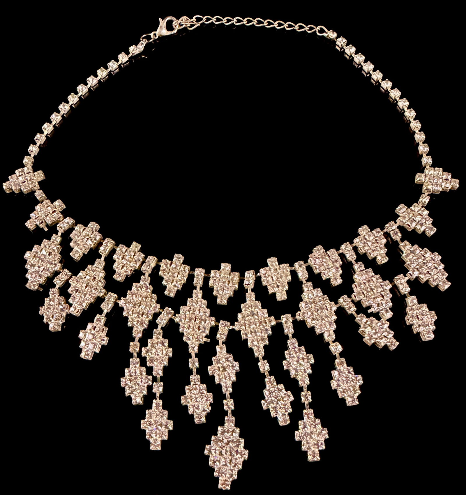 Silver-Toned Rhinestone Bib Fringe Necklace: A silver-toned costume jewelry bib necklace featuring a dramatic fringe design. The central decorative portion is composed of multiple articulated, cross-shaped drop elements. Each element is densely
