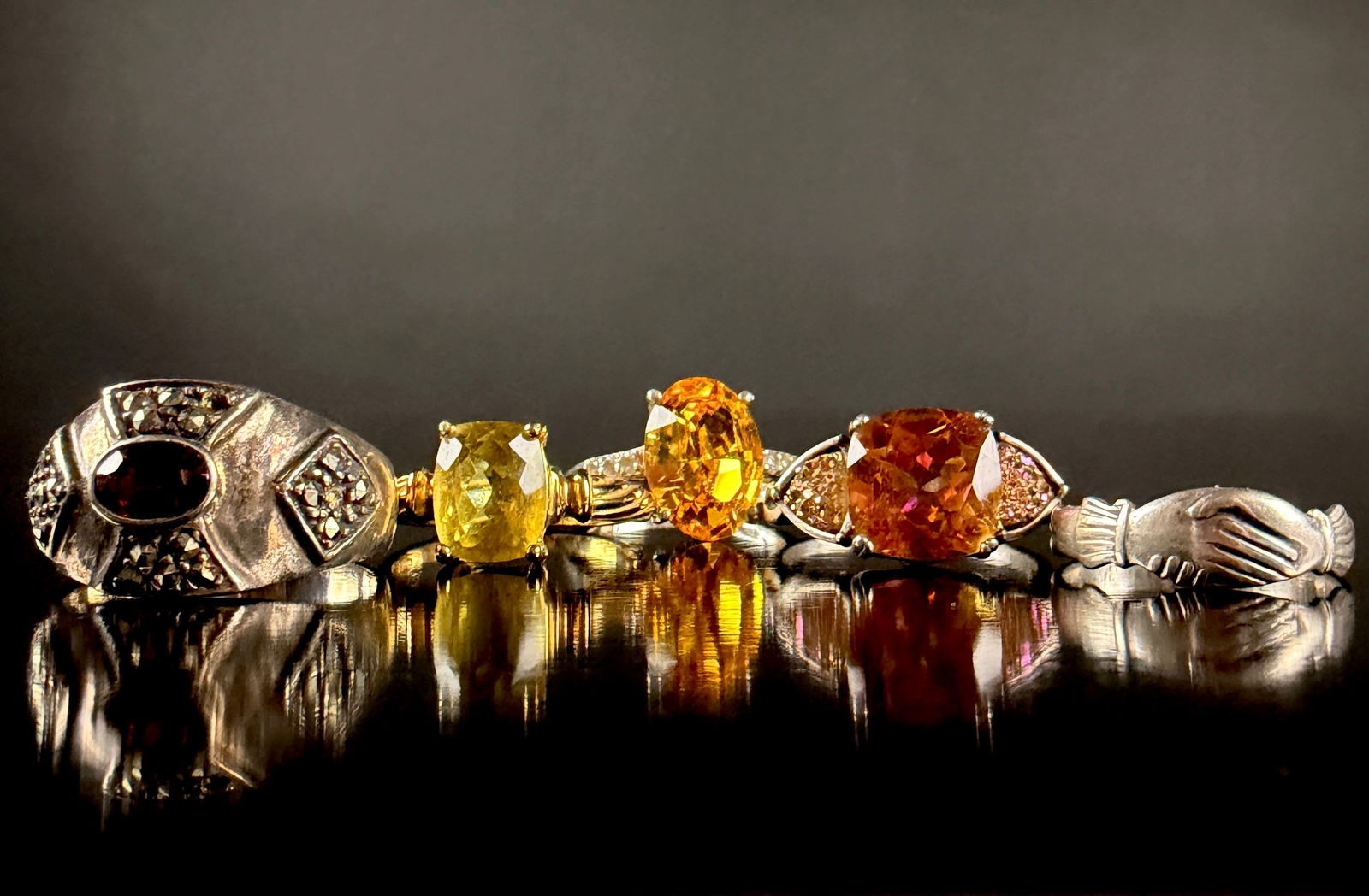 A Collection of Sterling Silver and Gemstone Rings: A collection of sterling silver rings featuring various faceted gemstones including citrine and sapphire. The group includes a ring with a large oval yellow gemstone in a prong setting, a cushion-cut