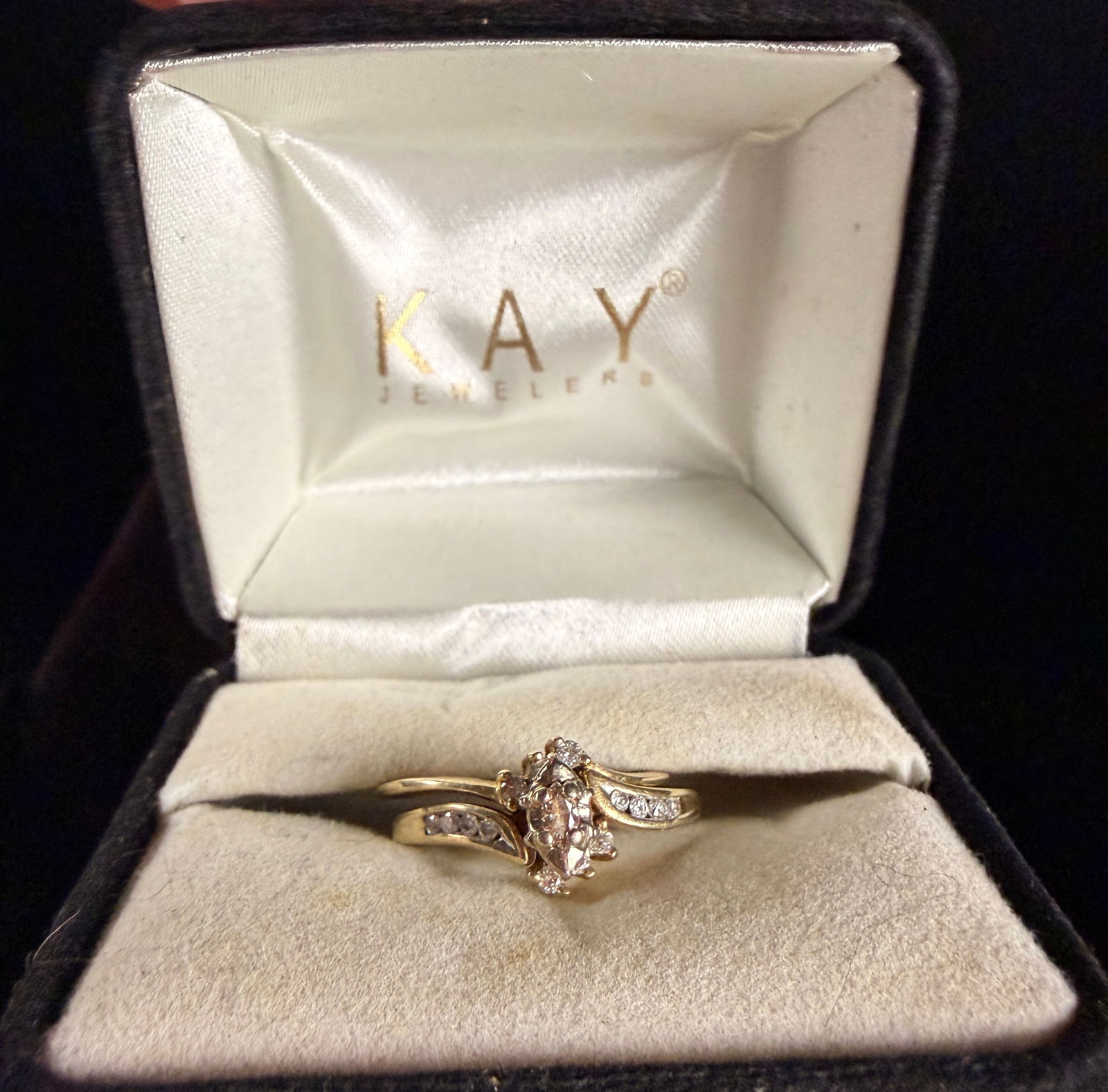 A Pair of Kay Jewelers 10k Yellow Gold Rings Forming a Marquise Diamond Bridal Set: ,A Kay Jewelers marquise diamond bridal set consisting of a central engagement ring and a coordinating wrap-style enhancer band. The engagement ring is constructed in 10k yellow gold and features a ma
