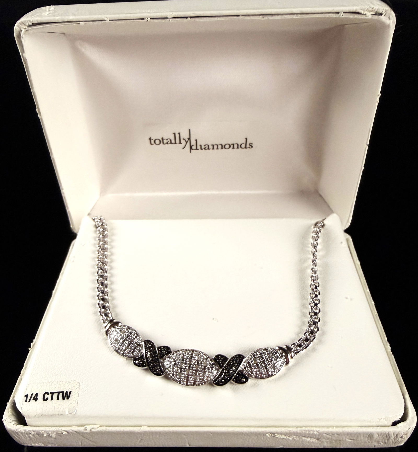 A Contemporary White Metal and Diamond Bib Necklace: A contemporary white metal necklace featuring a central bib-style decorative element. The design consists of three graduated oval sections pav?©-set with clear and black diamonds, separated by two pa