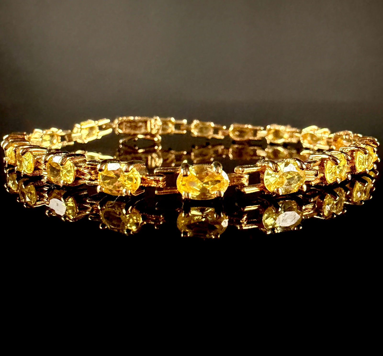 Amour Yellow Plated Sterling Silver Citrine Tennis Bracelet: An Amour yellow plated sterling silver citrine tennis bracelet. The piece is constructed of gold-plated sterling silver and features multiple prong-set, oval-cut yellow citrine stones arranged in a co