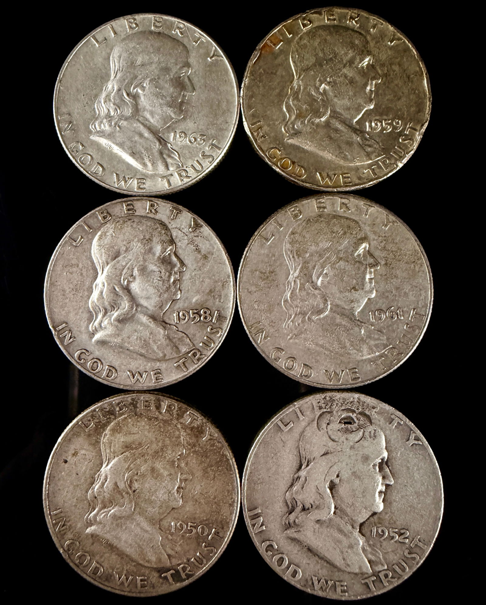 An Assortment of Franklin Silver Half Dollars: An assortment of United States Franklin Half Dollars struck in 90 percent silver. The obverse of each coin features the profile of Benjamin Franklin, inscribed with LIBERTY, IN GOD WE TRUST, and the y