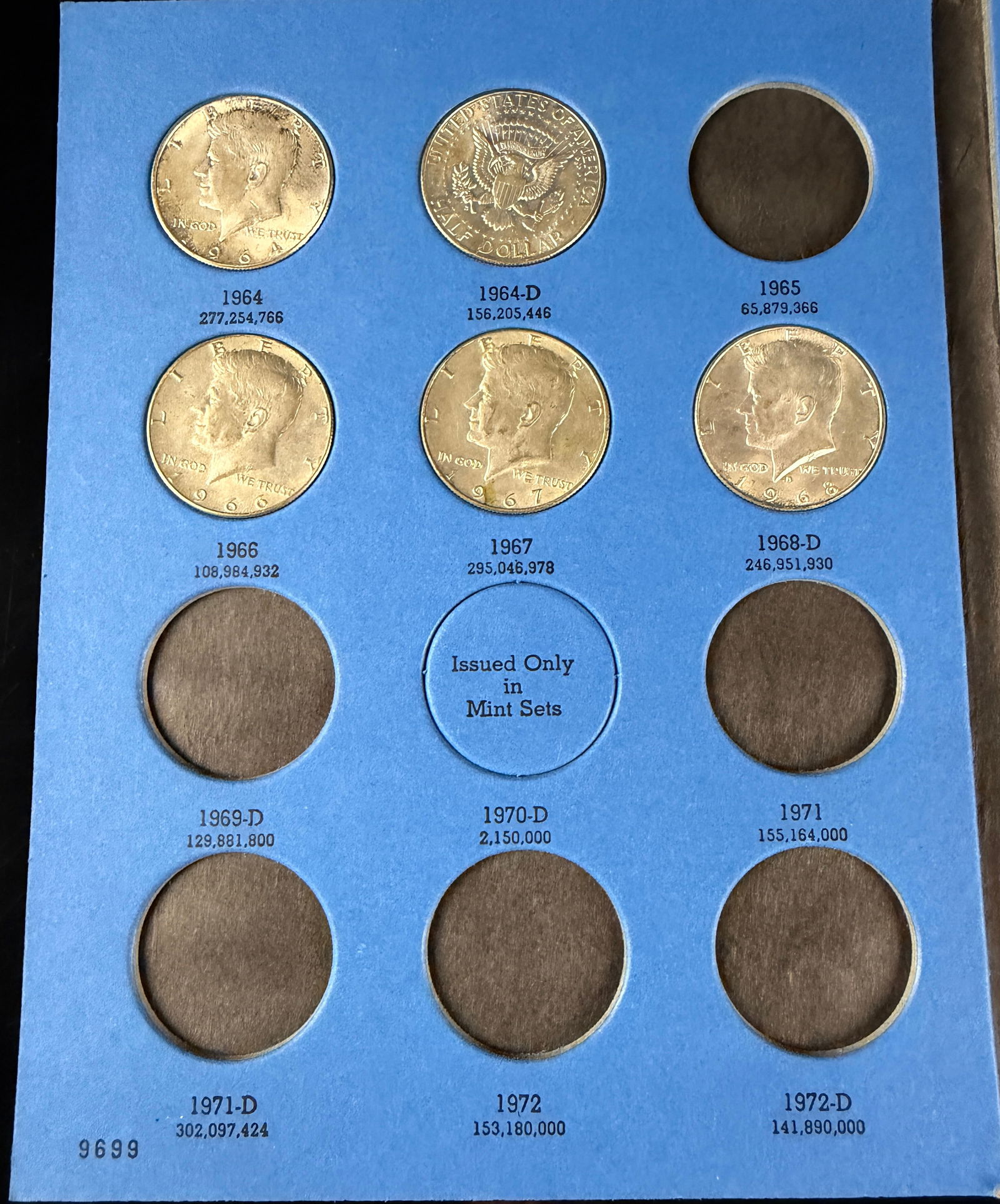 A Partial Collection of John F. Kennedy Half Dollars in an Official Whitman Coin Folder: This partial collection of 5 United States Kennedy Half Dollars is housed in an Official Whitman Coin Folder, Number One, Model 9699, designed for the years 1964 through 1985. The blue cardboard folde